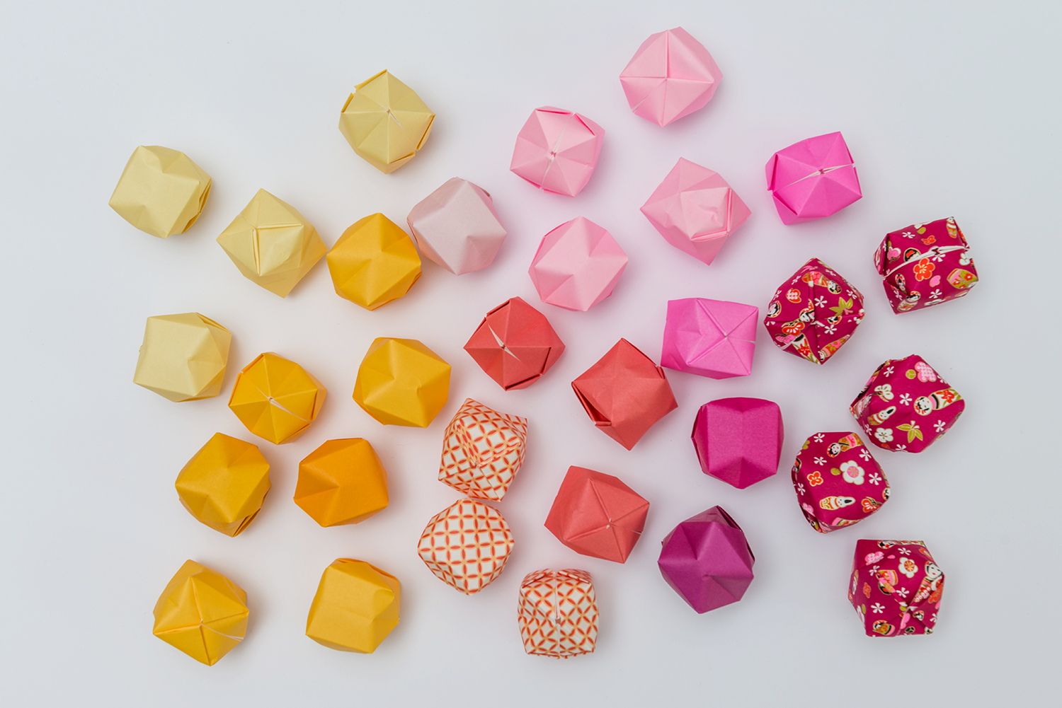 Bunte Origami-Stücke liegen auf einem weißen Hintergrund.