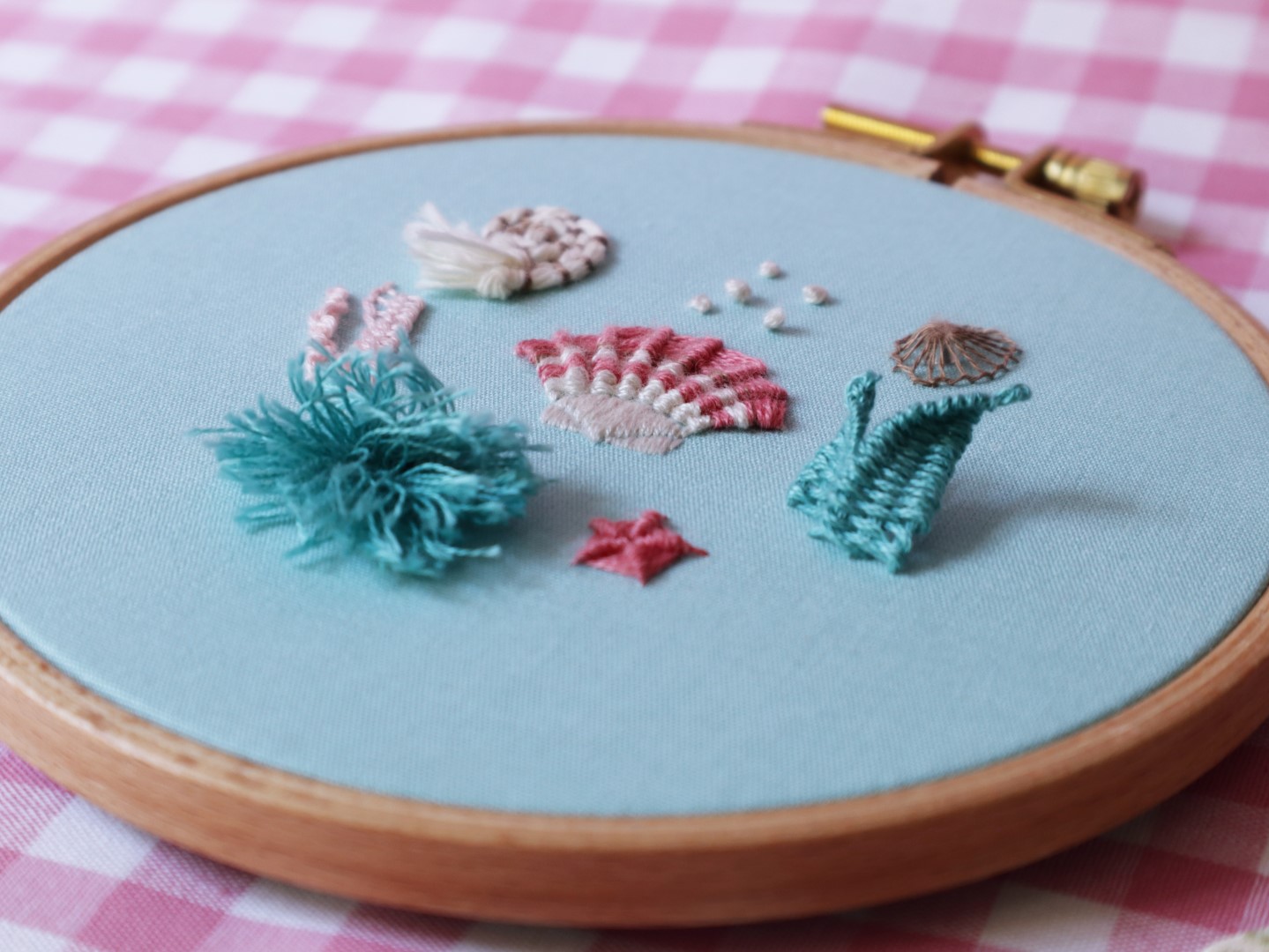 Embroidered shells and marine animals on a blue fabric frame.