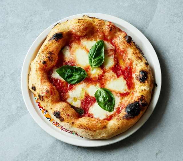 Pizza served with tomato sauce, mozzarella and fresh basil.