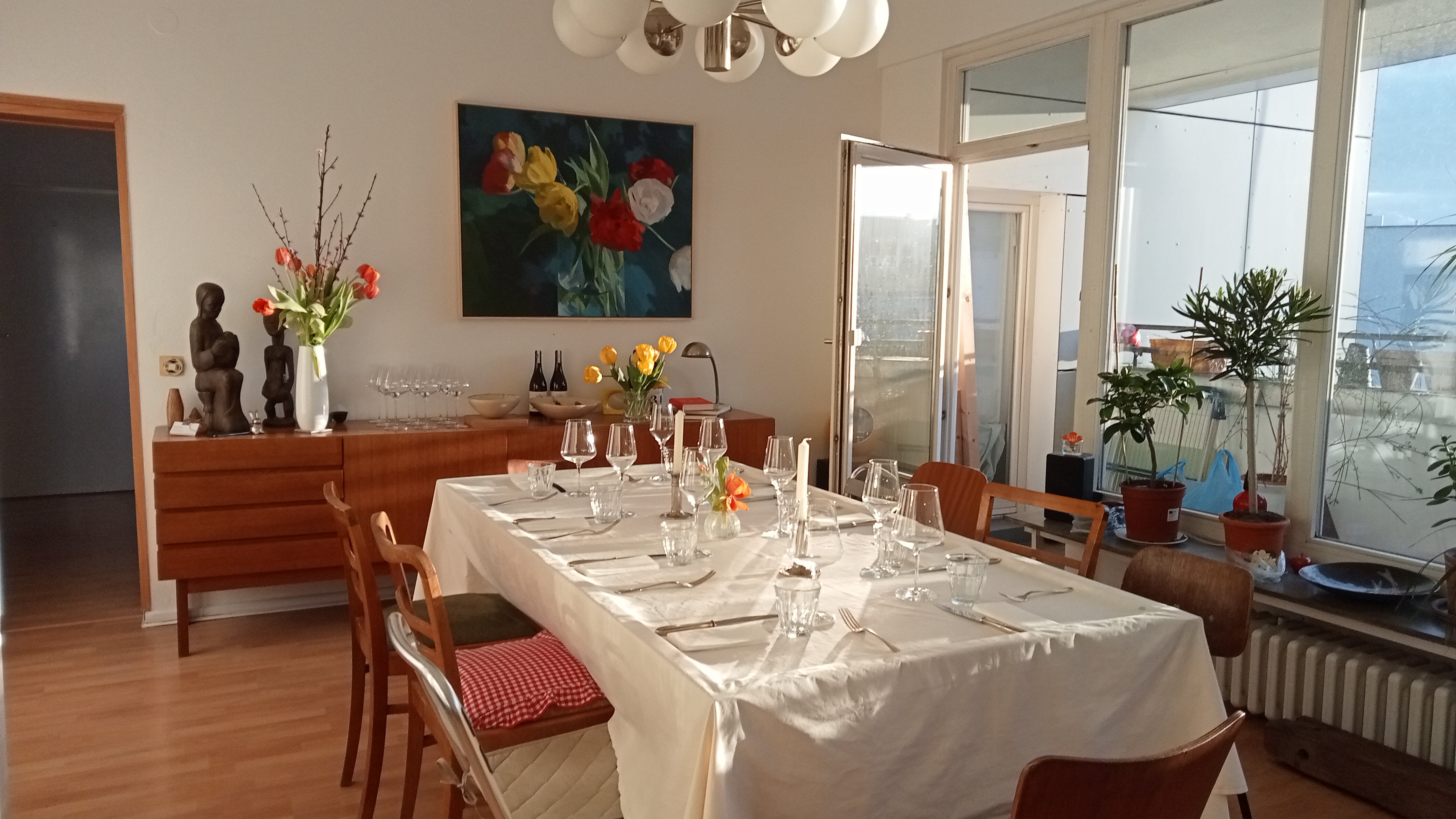 Dining room table set, blooming plants, bright apartment.