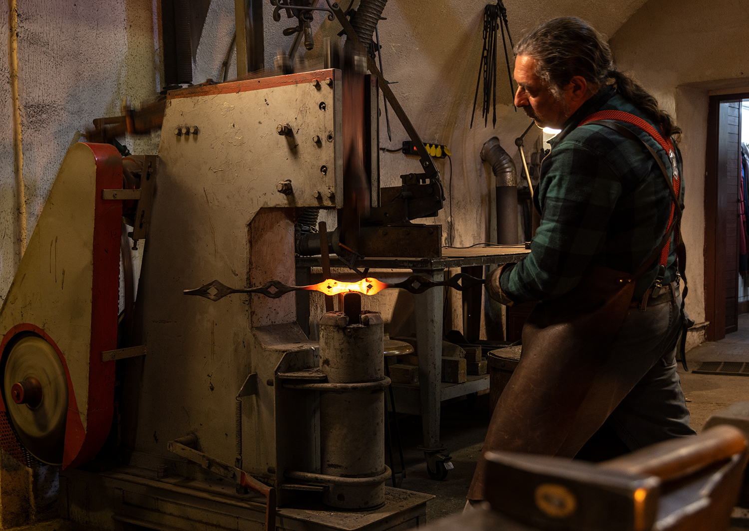 Schmiedehammer processes glowing metal in a workshop.