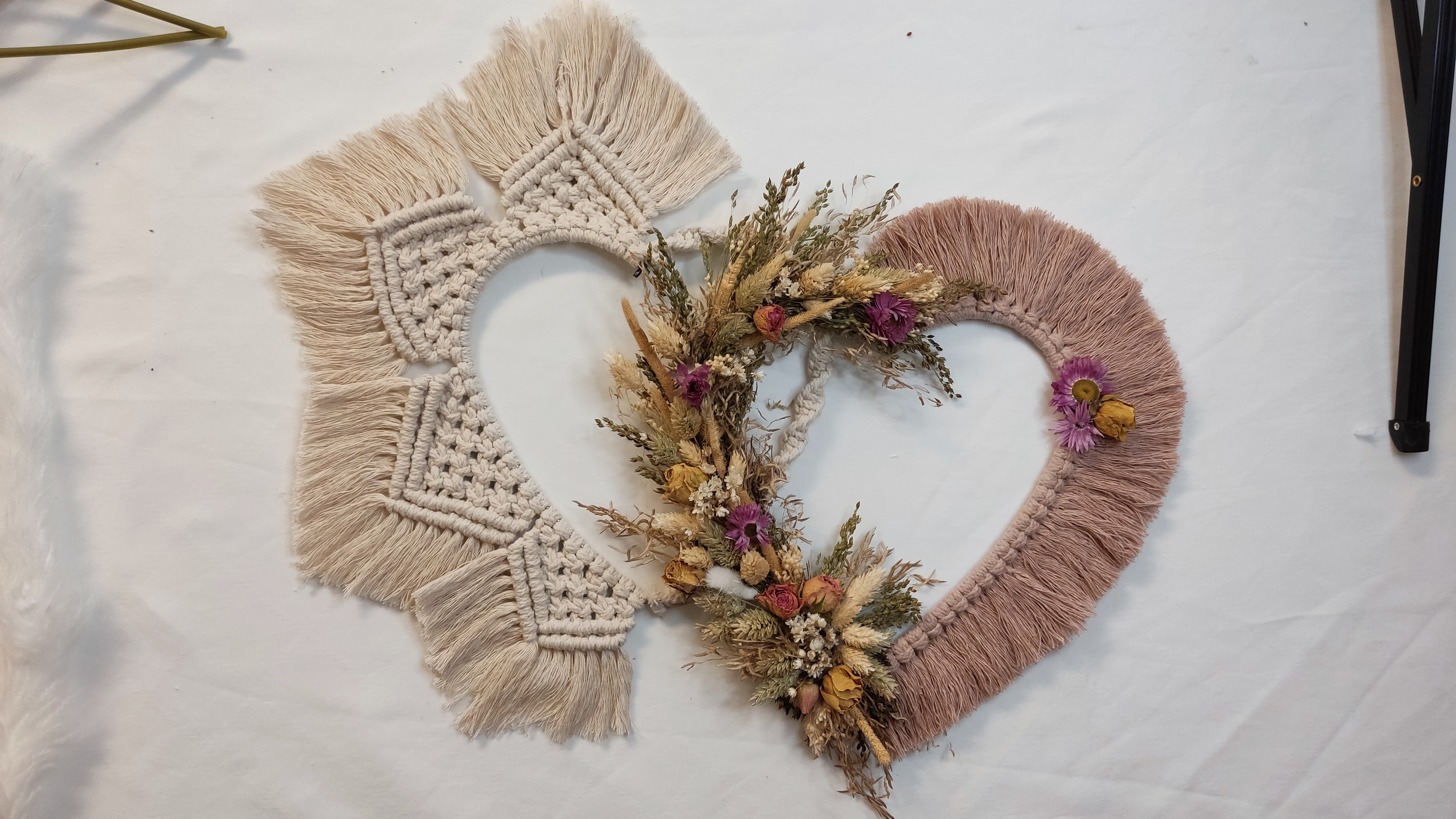 Herzförmige Wanddekorationen aus Makramee und Trockenblumen.