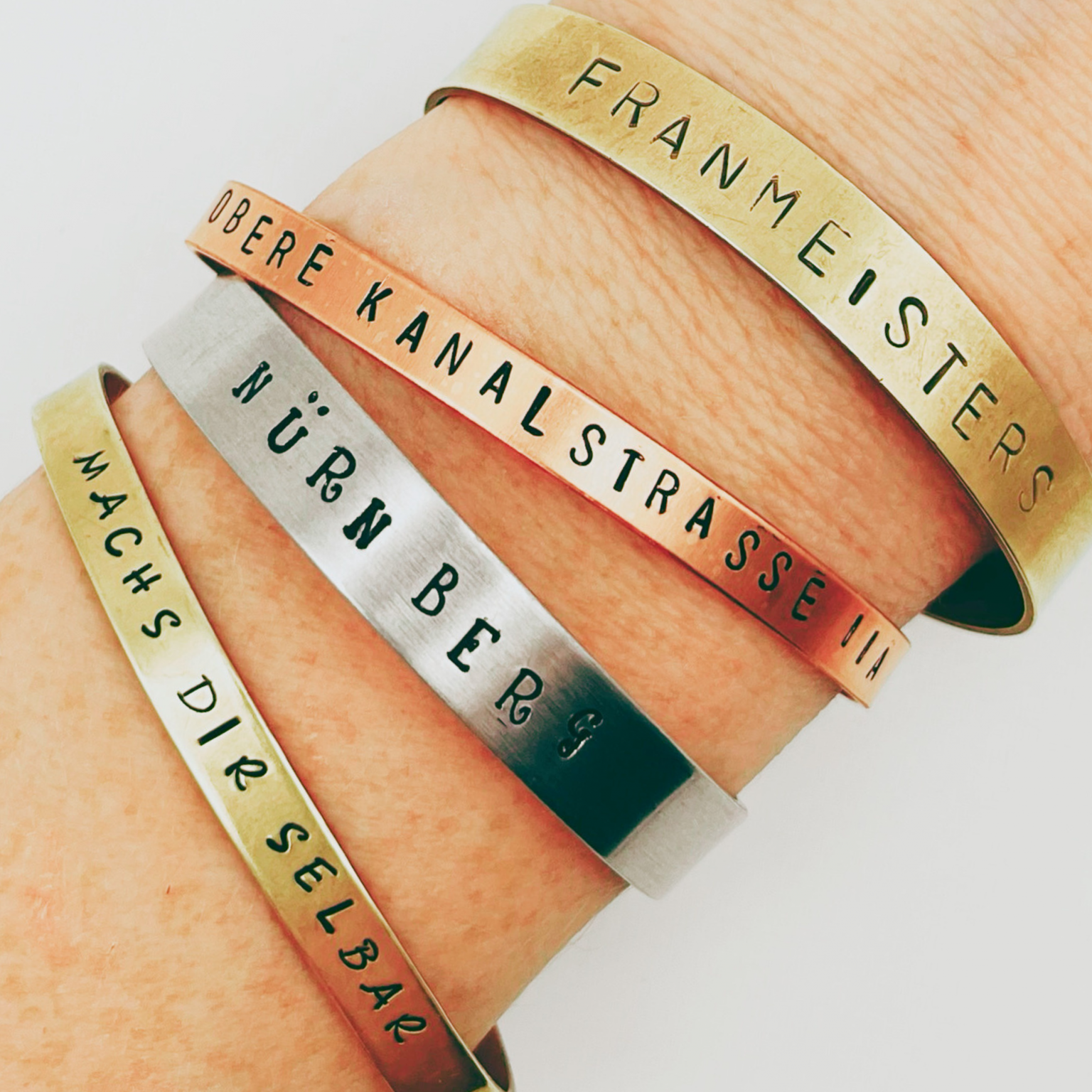 Bracelets with engraved names rest on a wrist.
