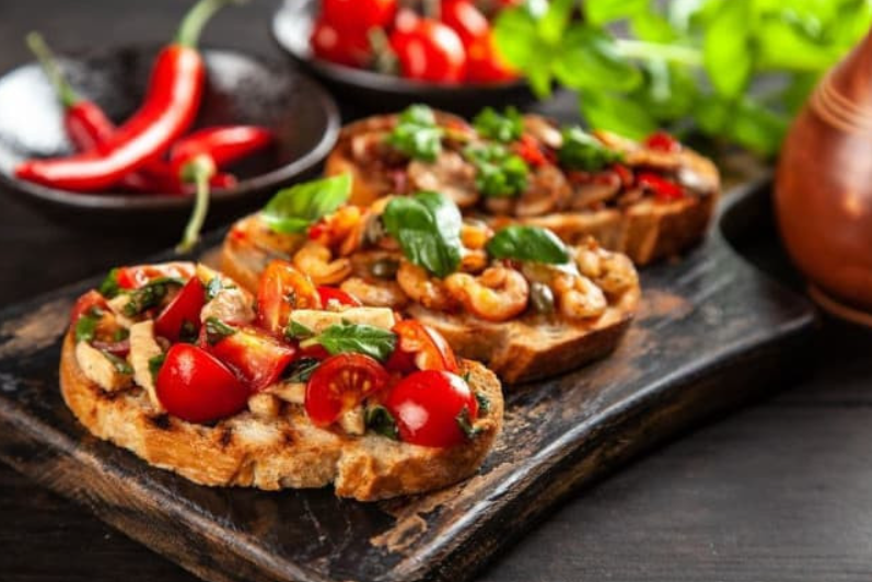 Geröstetes Brot mit frischem Gemüse und Kräutern serviert.