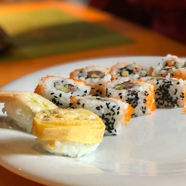 Sushi rolls are laid out on a white plate, appetizingly arranged.