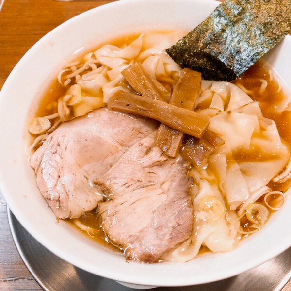 A bowl of ramen with meat and vegetables in broth.