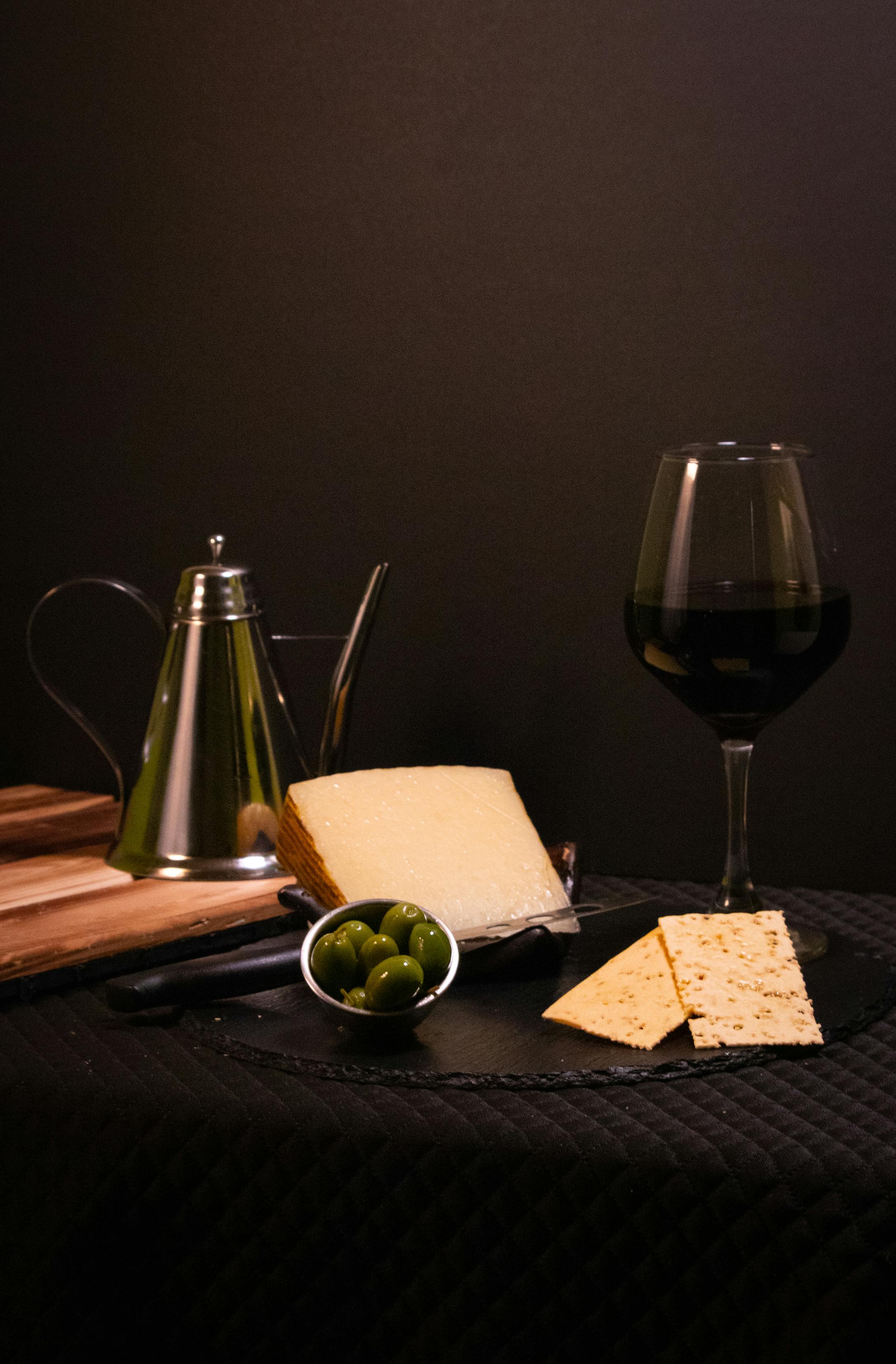 Käse, Oliven und Wein auf einem Tisch serviert.