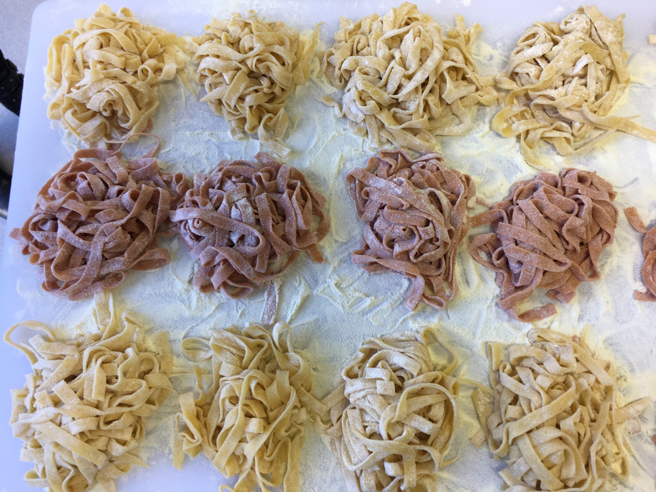 Hausgemachte Pasta-Nester liegen auf einem bemehlten Tisch.