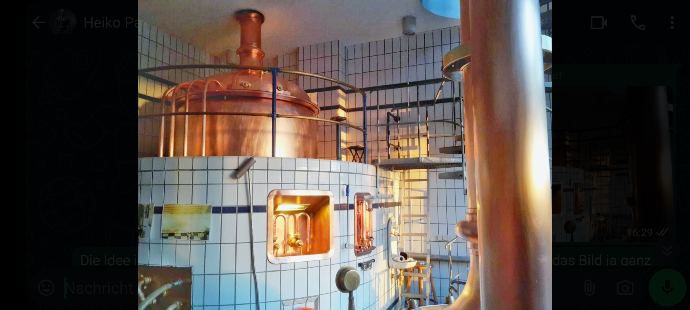 Kupferne Brauanlage in hell erleuchtetem Raum mit Treppe.
