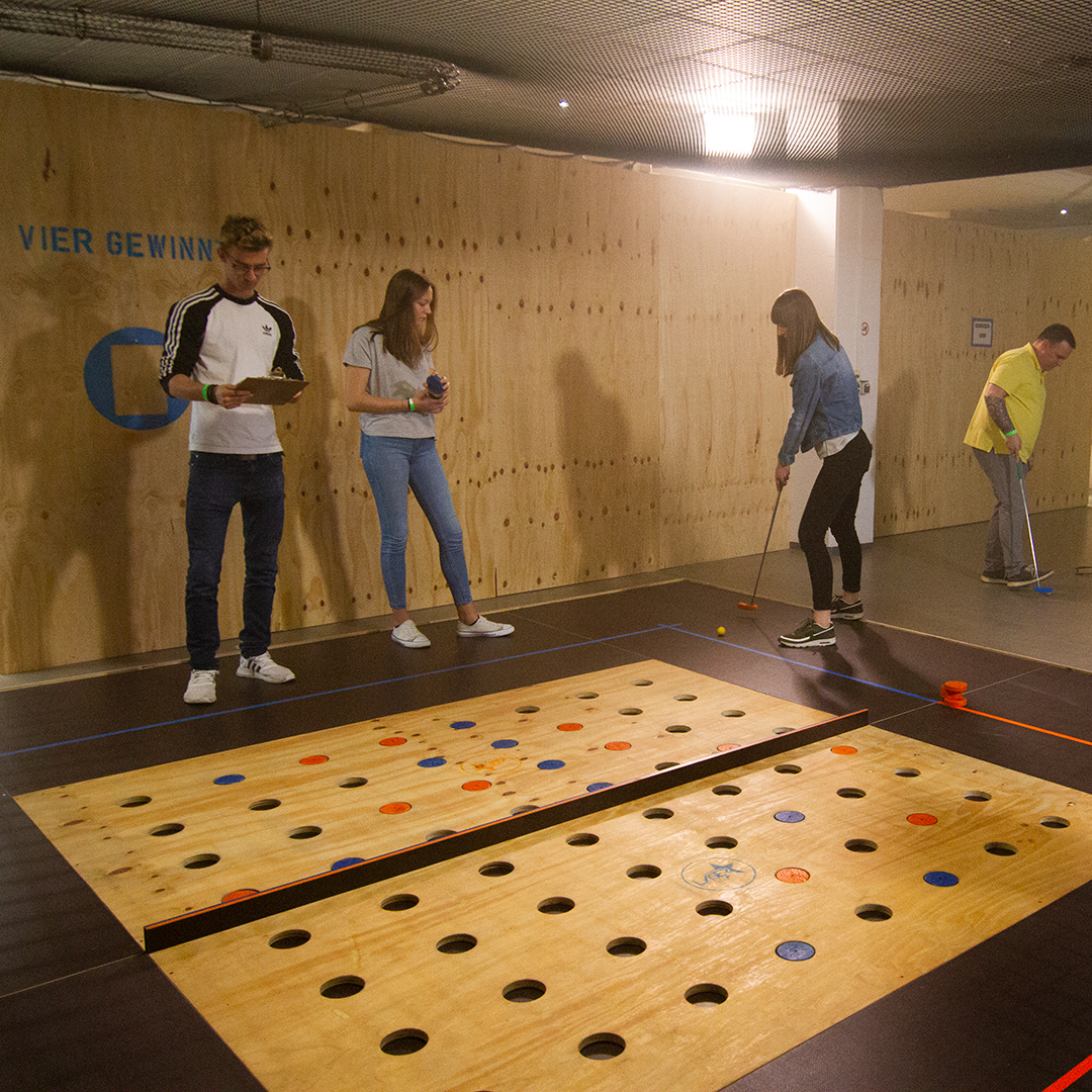 People playing a mini-golf type game indoors.