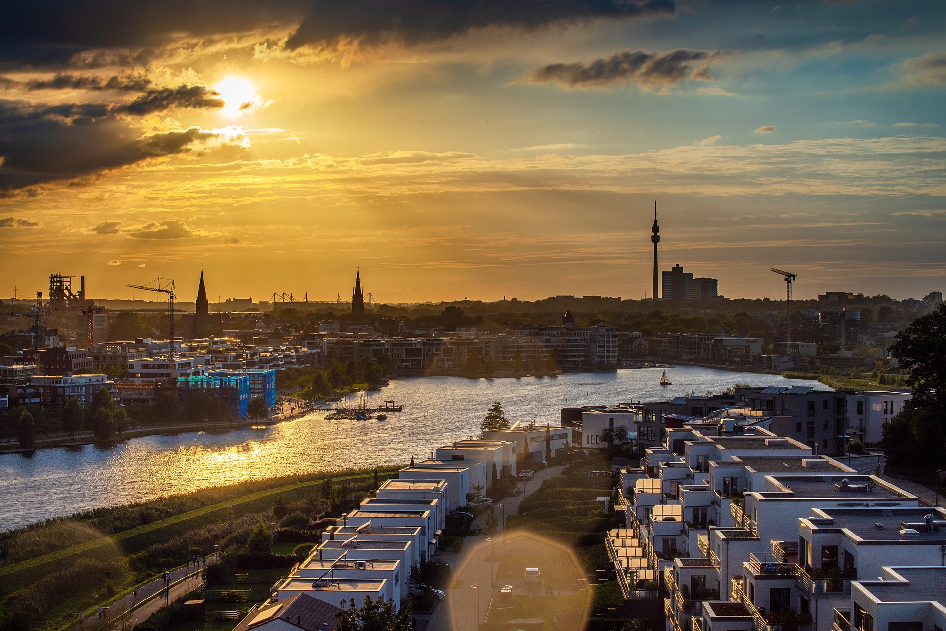 Stadtansicht mit Sonnenuntergang, Wasser und modernen Gebäuden.