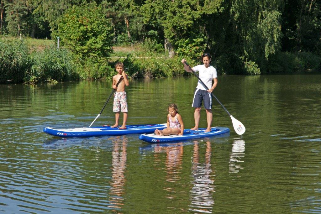 Zwei Kinder und ein Erwachsener paddeln auf See.