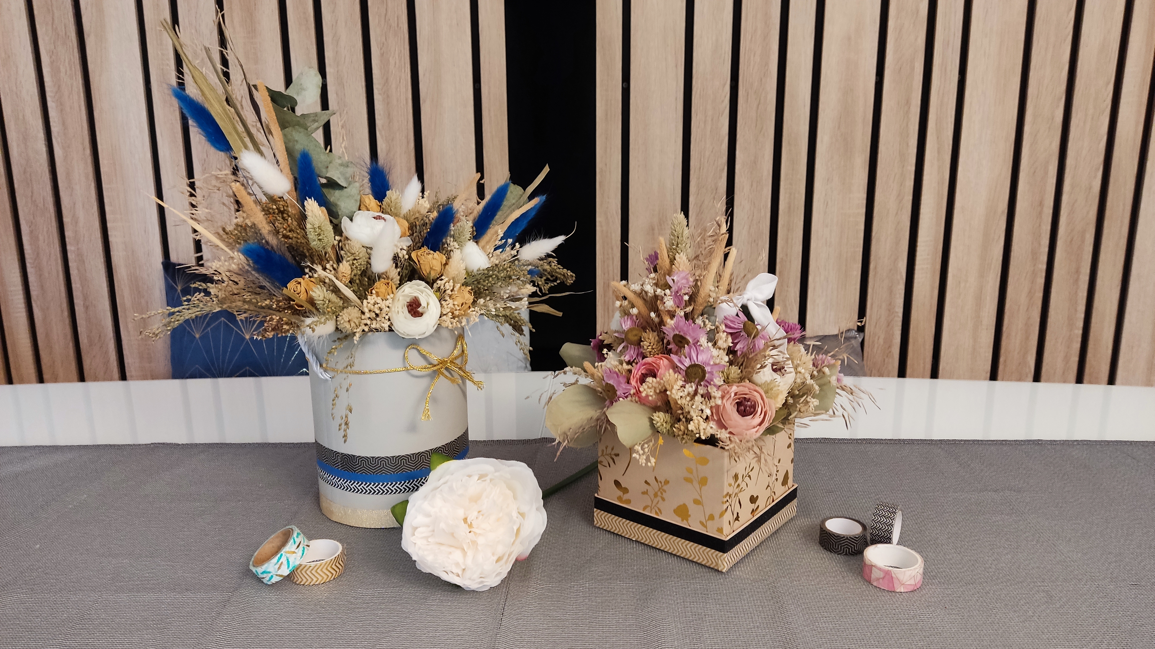 There are two flower arrangements on a table.