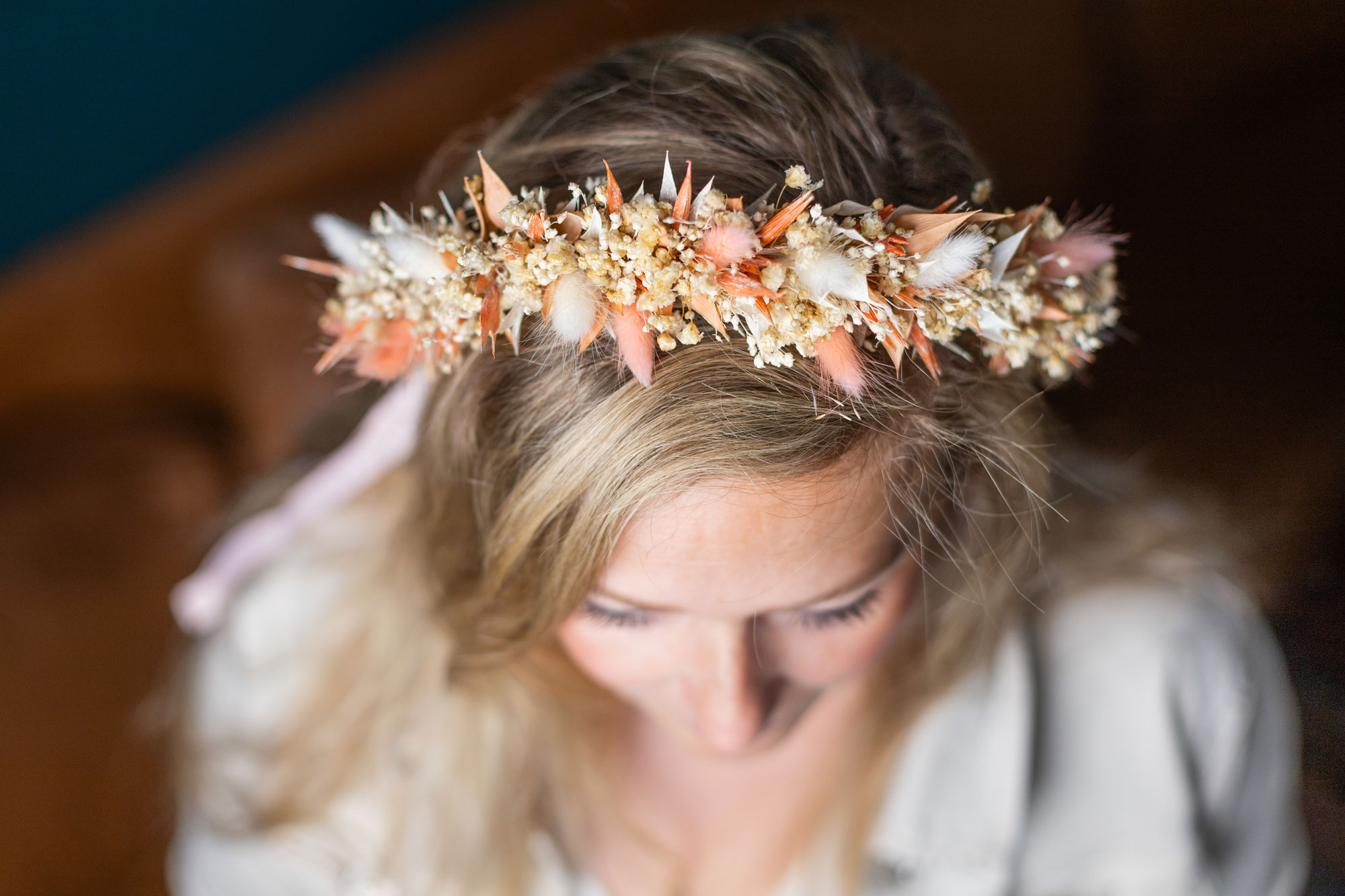 Blumenkranz schmückt Haare, während die Person nach unten schaut.