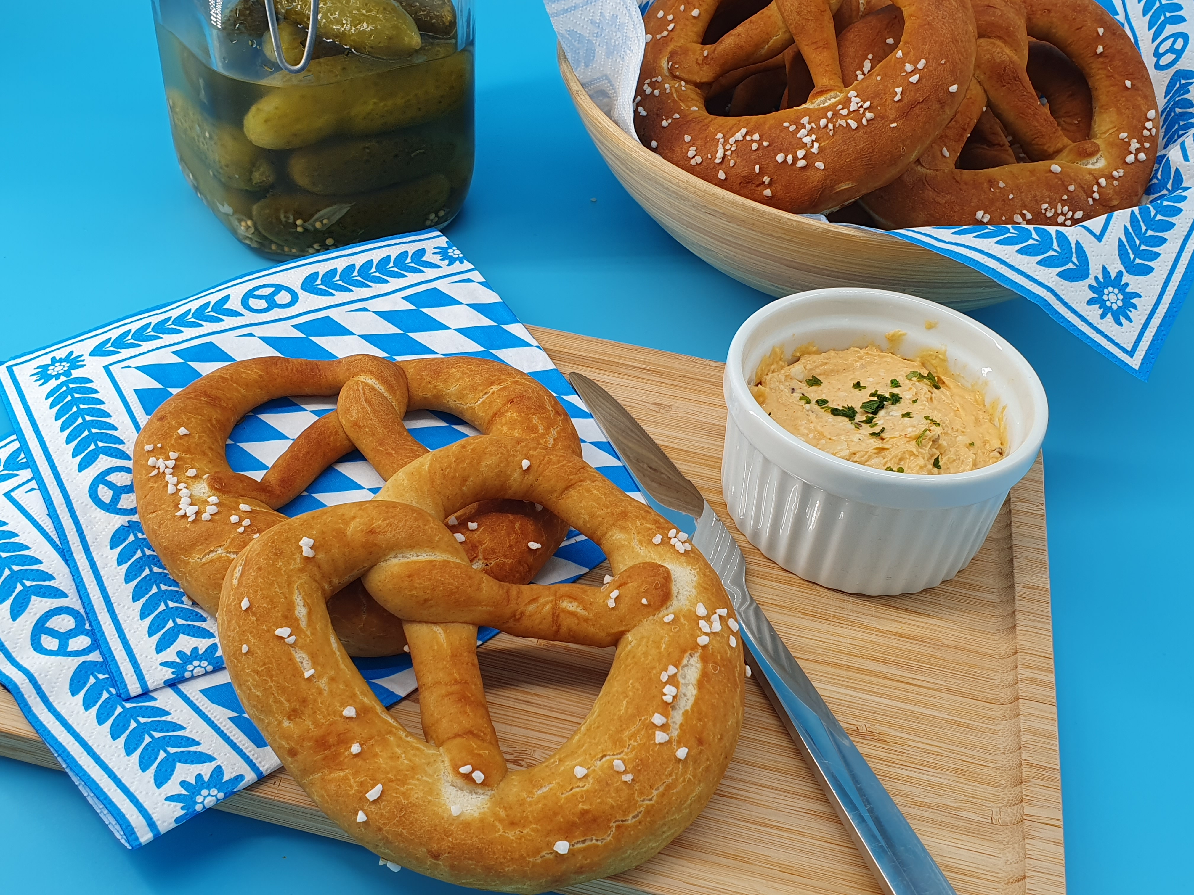 Pretzels and Obatzda on a wooden board and a blue background
