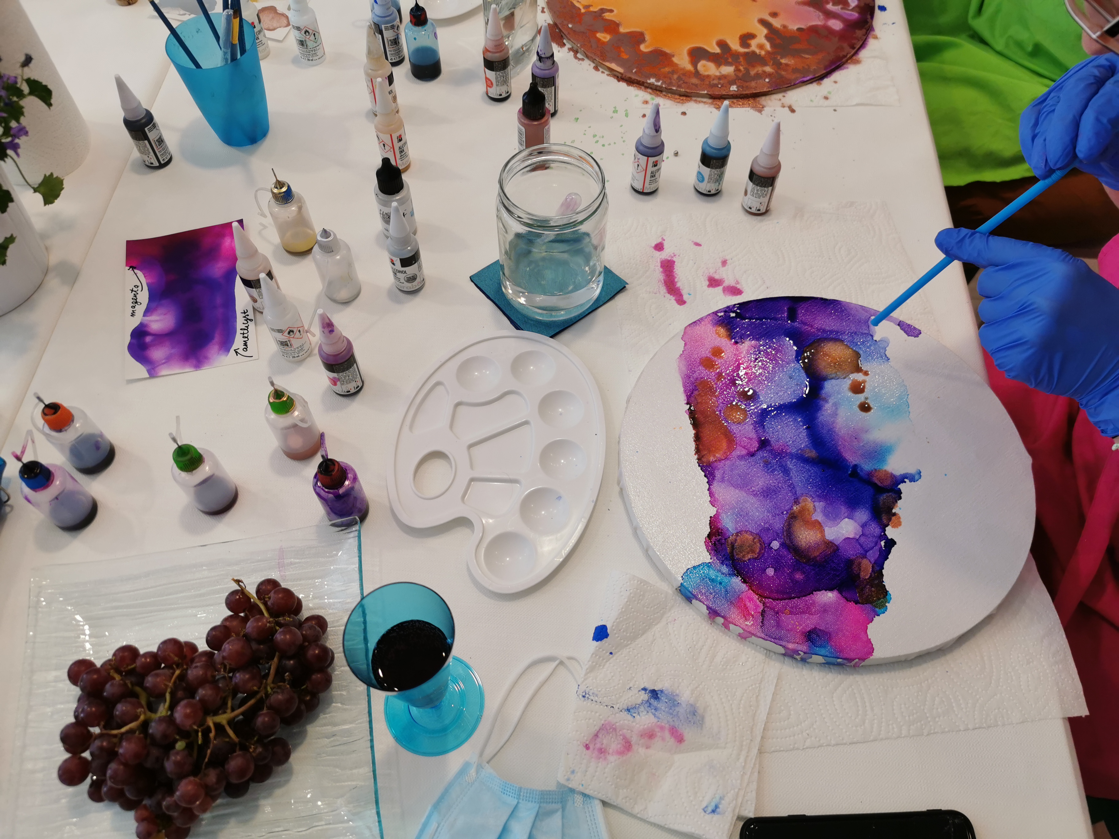 Colored ink is applied to a canvas. Environment with painting supplies.