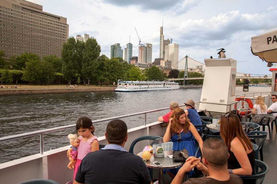 People sit on a boat as it passes by the shore.