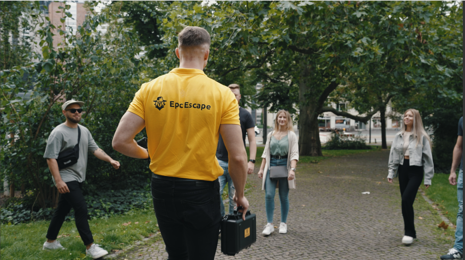 Person trägt gelbes Shirt, führt Gruppe in Park.