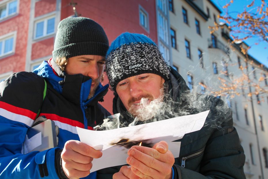 Two men study strained smoking paper outdoors.