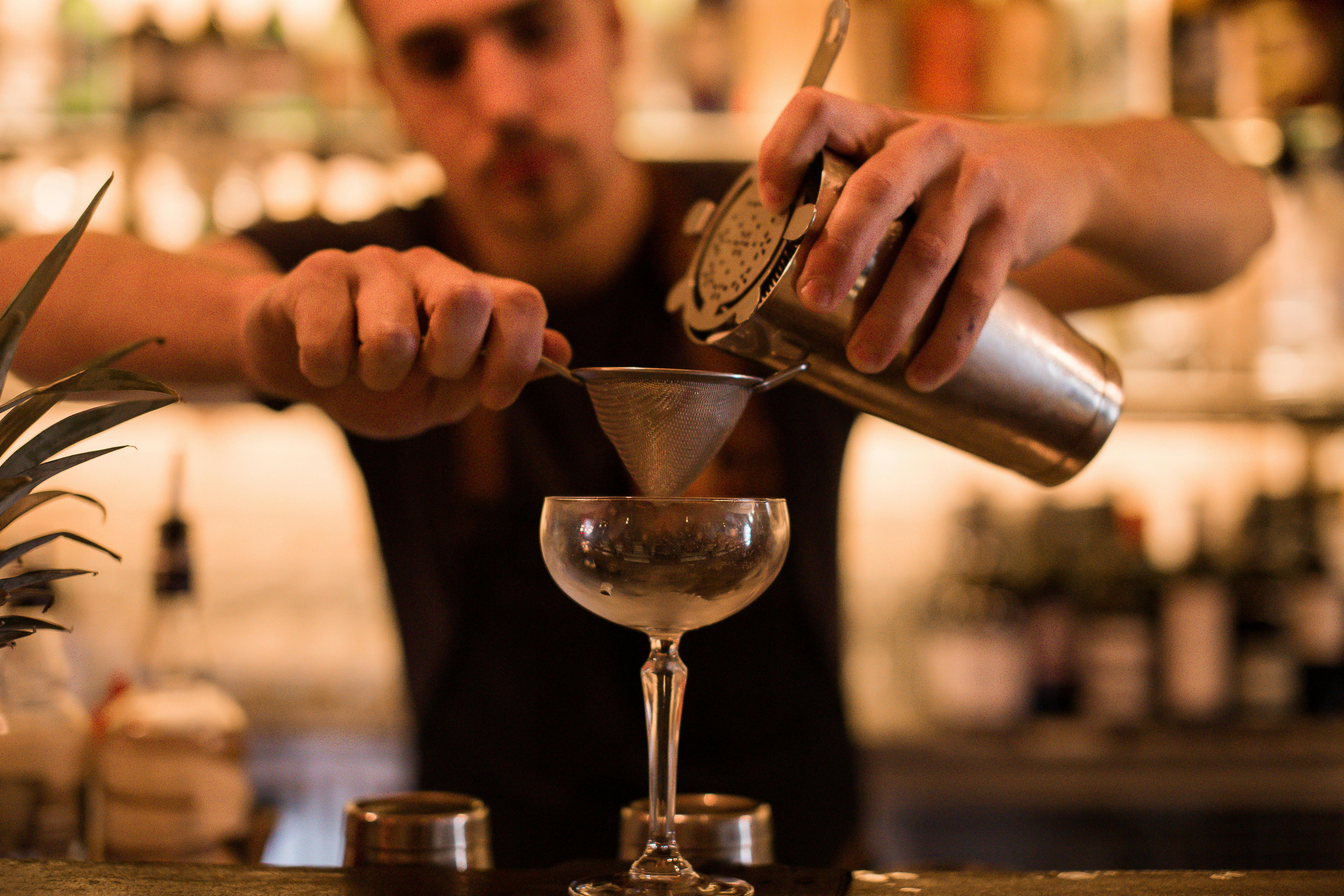 Barkeeper seiht Cocktails in ein Glas in einer Bar.