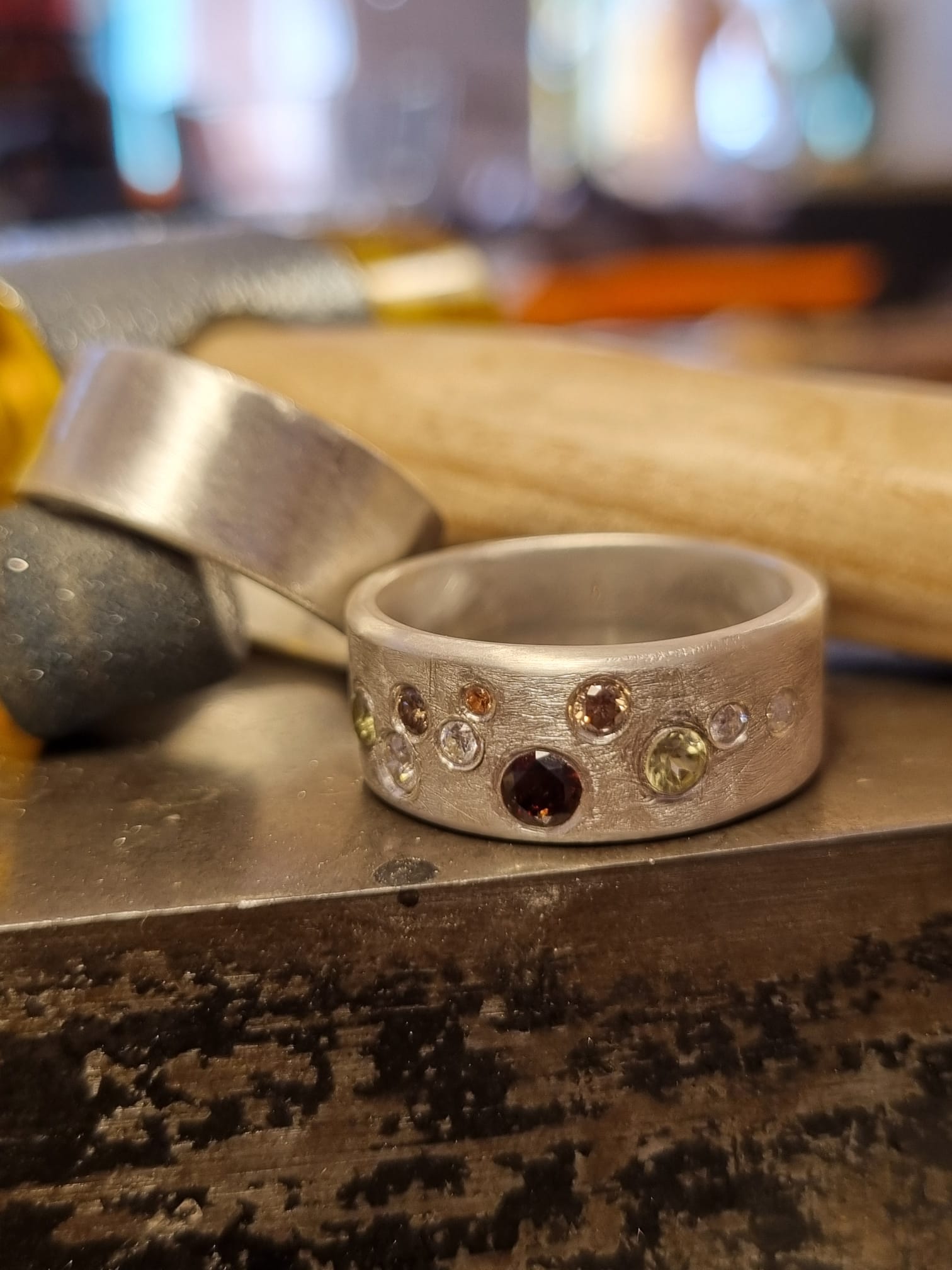 Ein Ring mit Edelsteinen liegt auf einer Metalloberfläche.