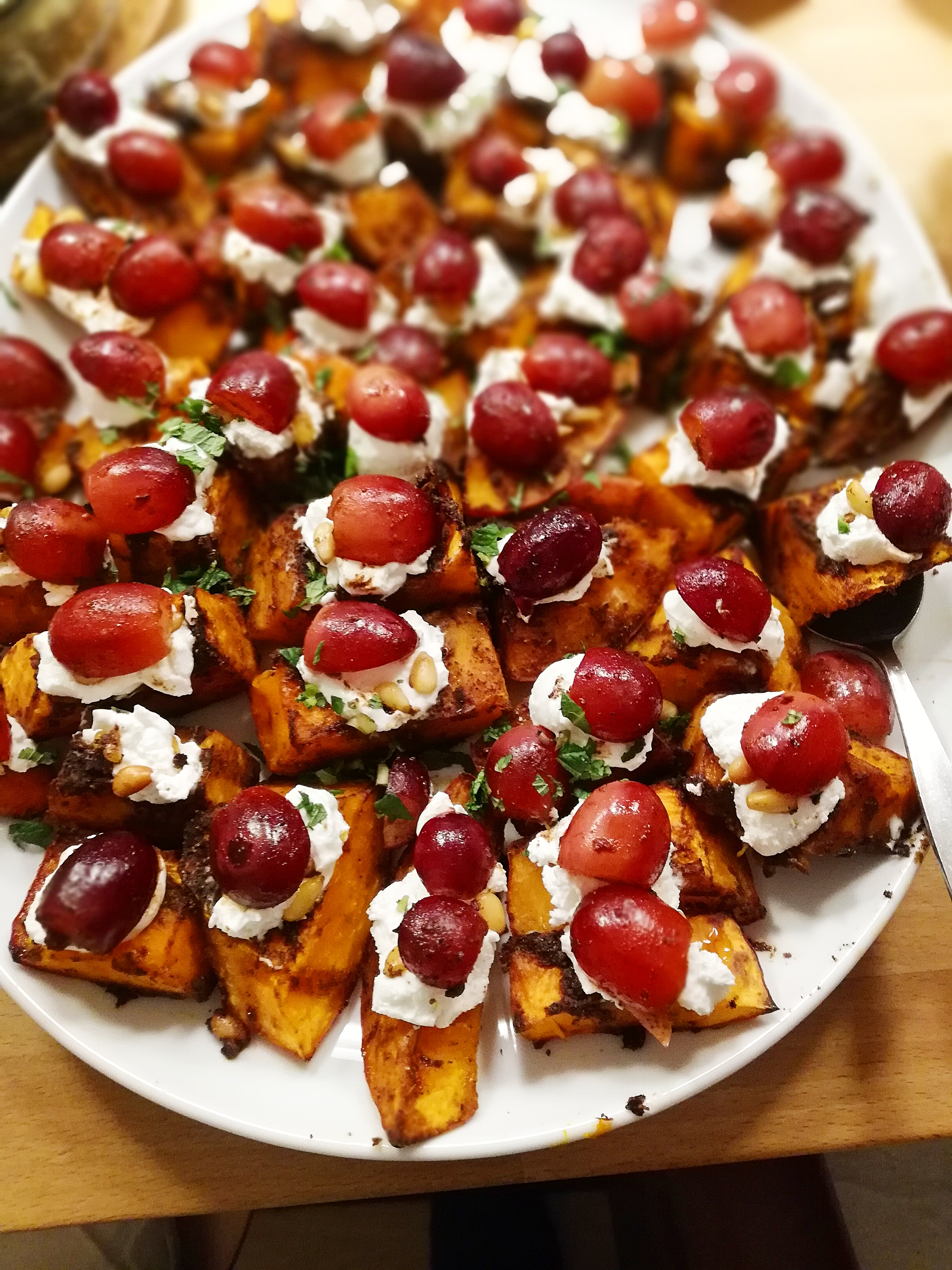 Roasted sweet potato pieces with grapes and cream cheese topping.