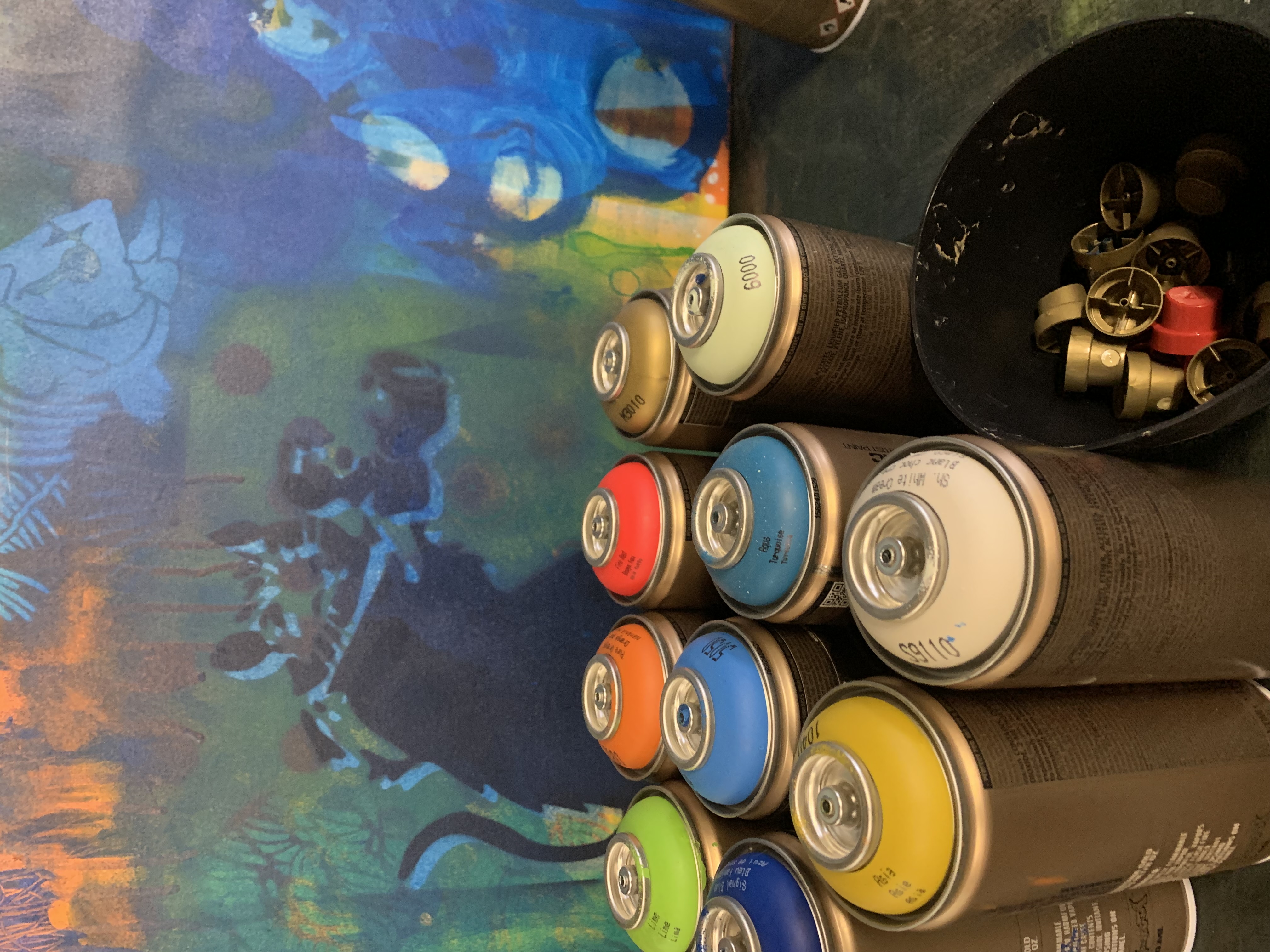 Spraydosen stehen vor einem bunten Graffiti-Hintergrund.