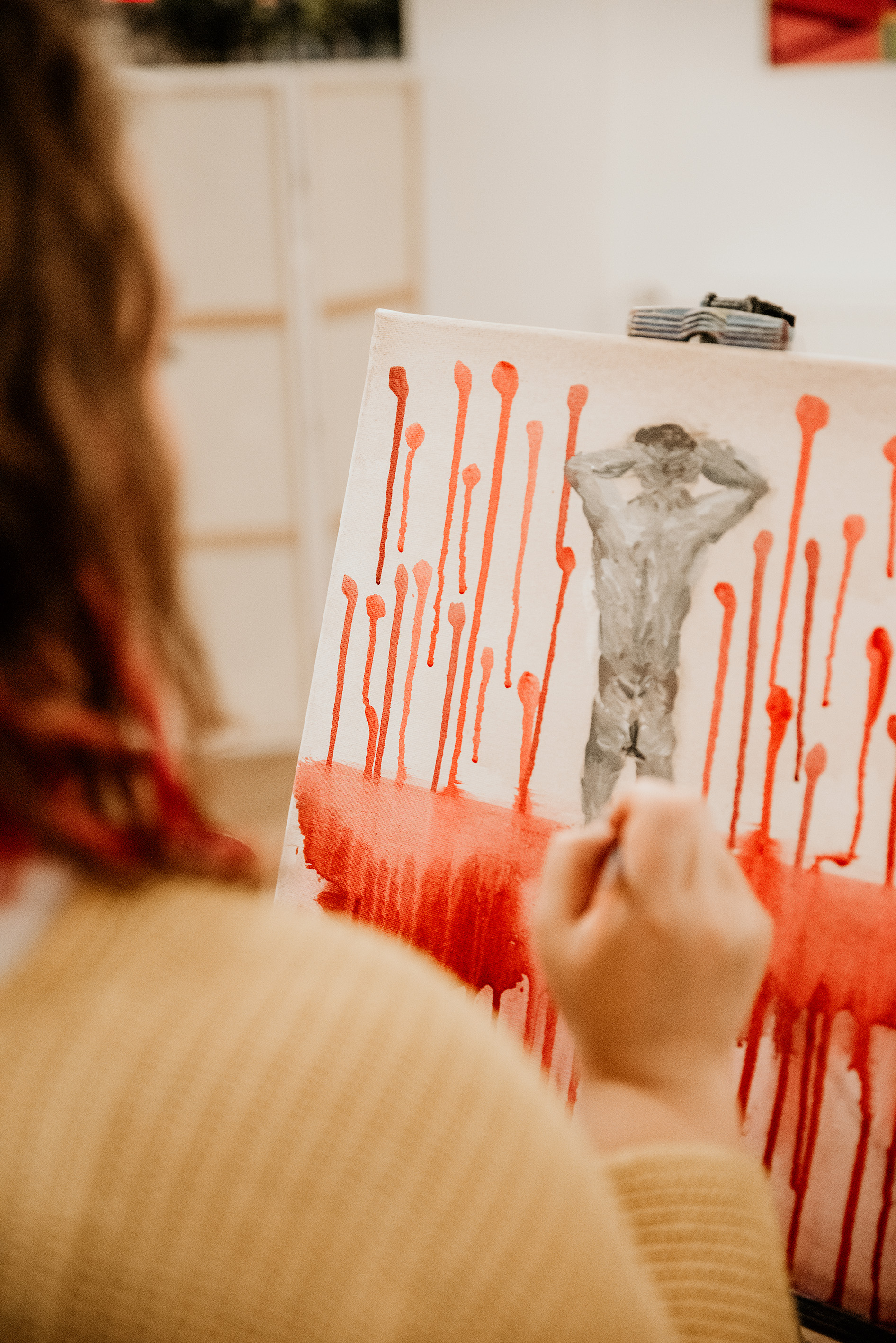 A person paints a bloody background on canvas.