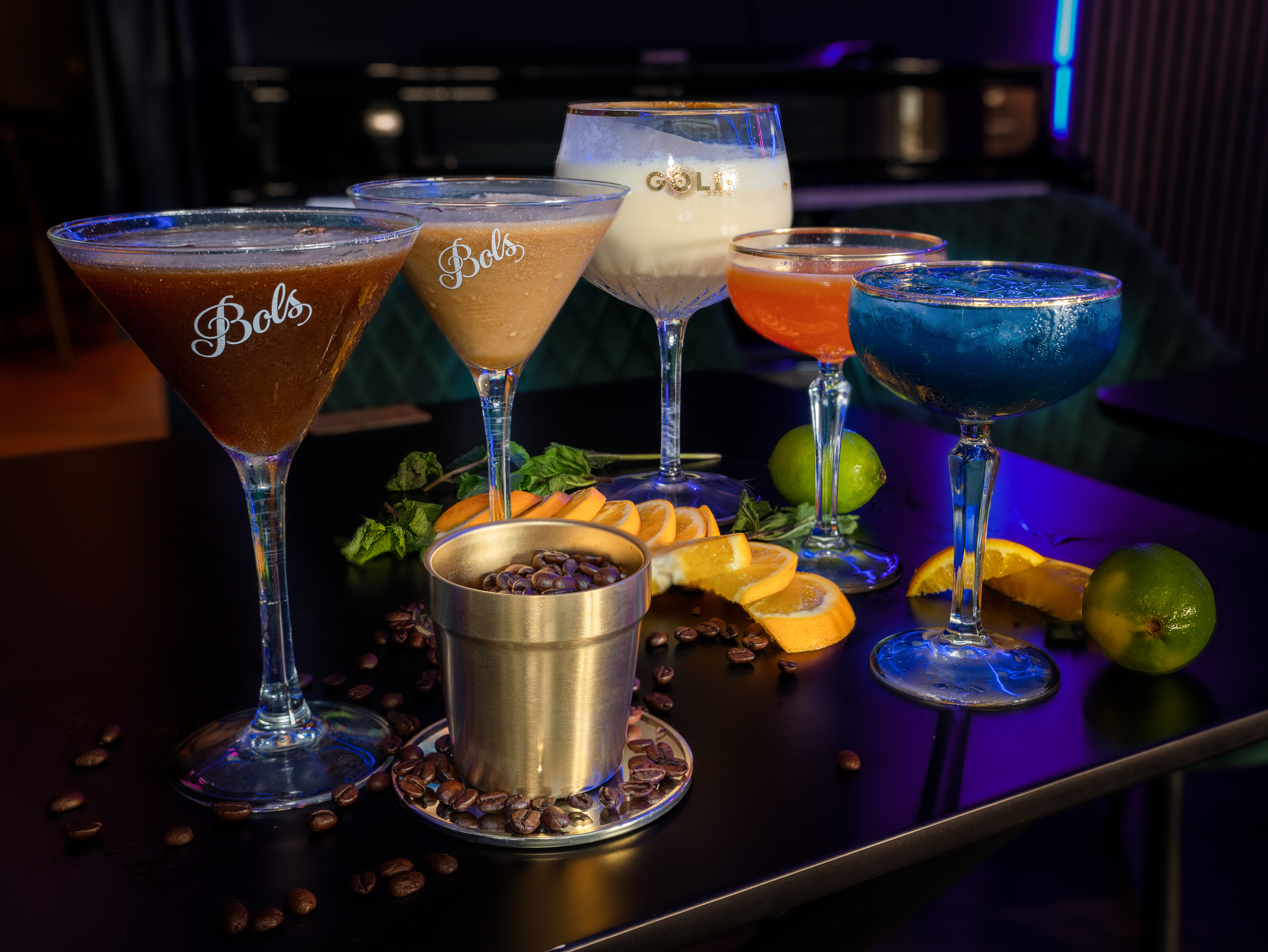Fünf bunte Cocktails auf einem Tisch.