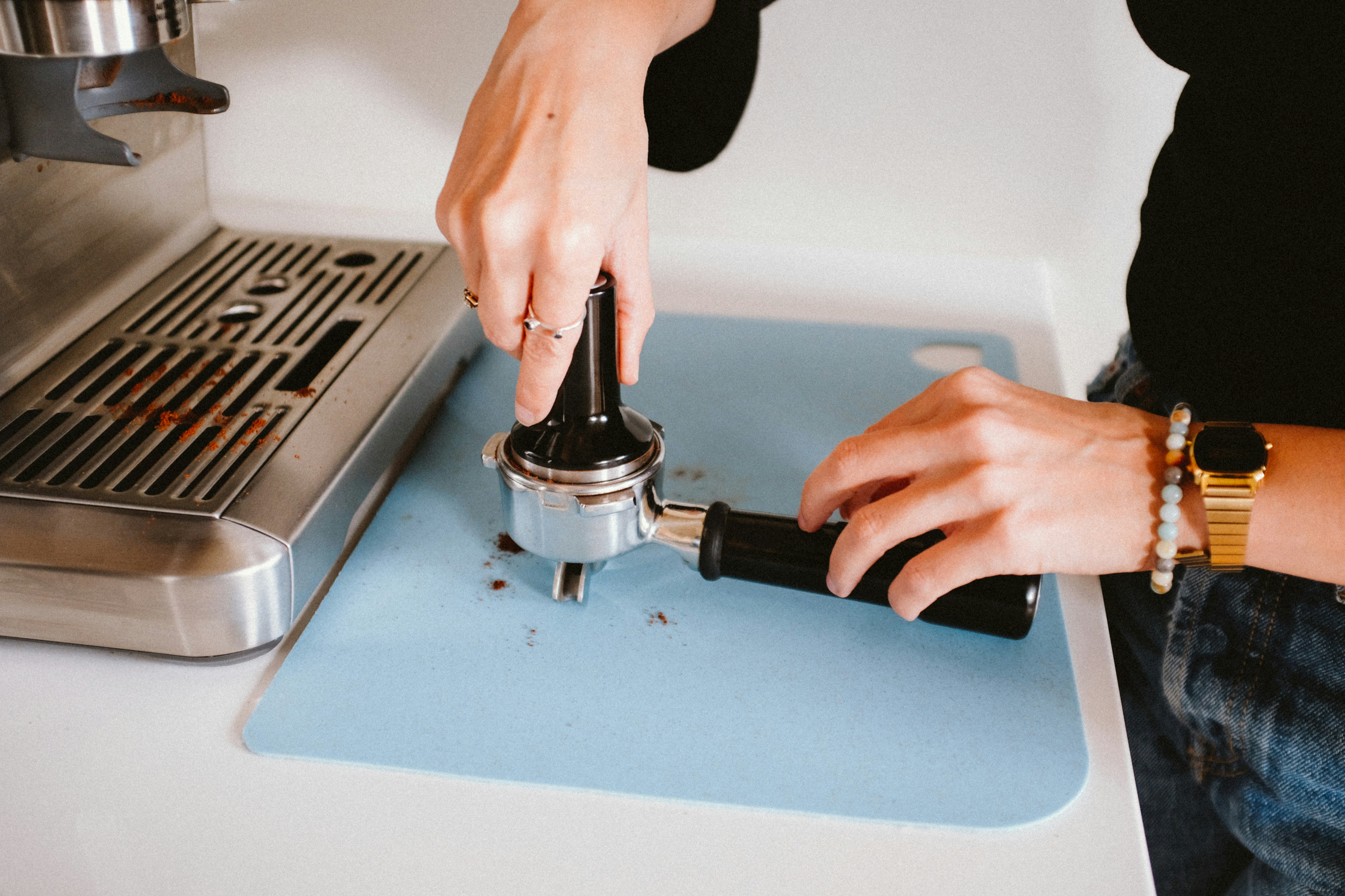 Eine Hand drückt einen Kaffeetamper auf einen Siebträger.