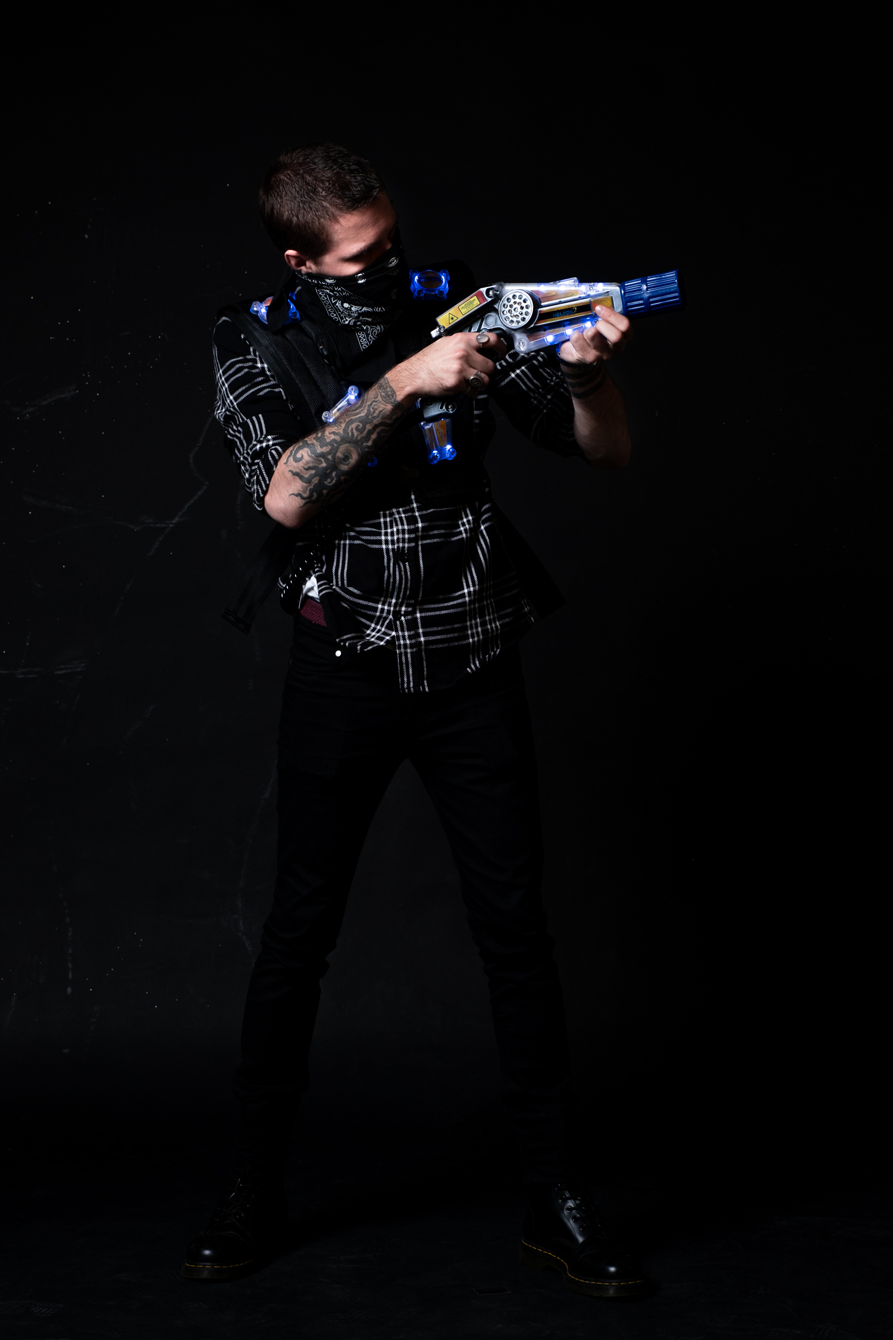 Person aiming laser tag gun in dark area.