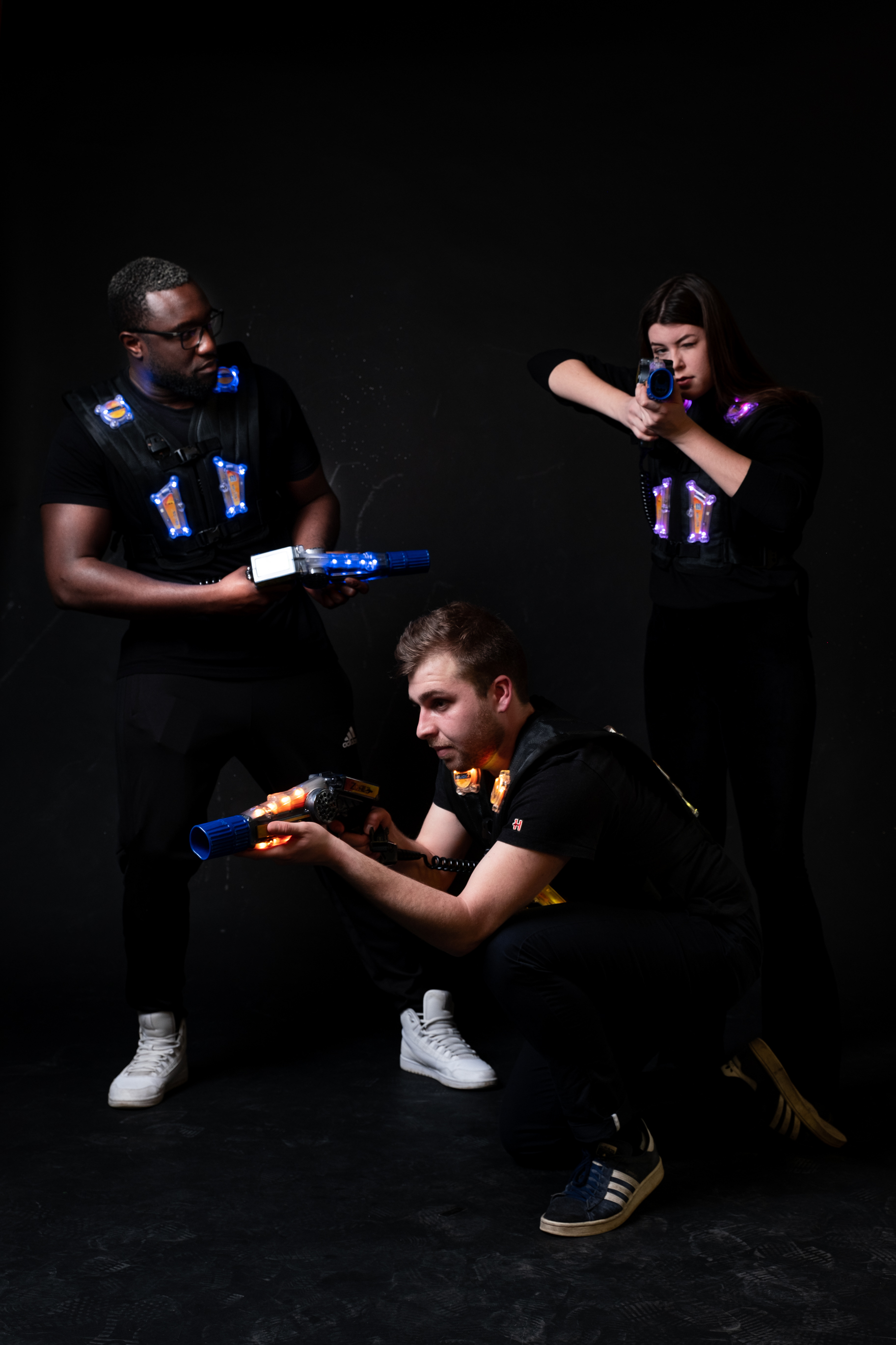 Two people play laser tag in a dark room.