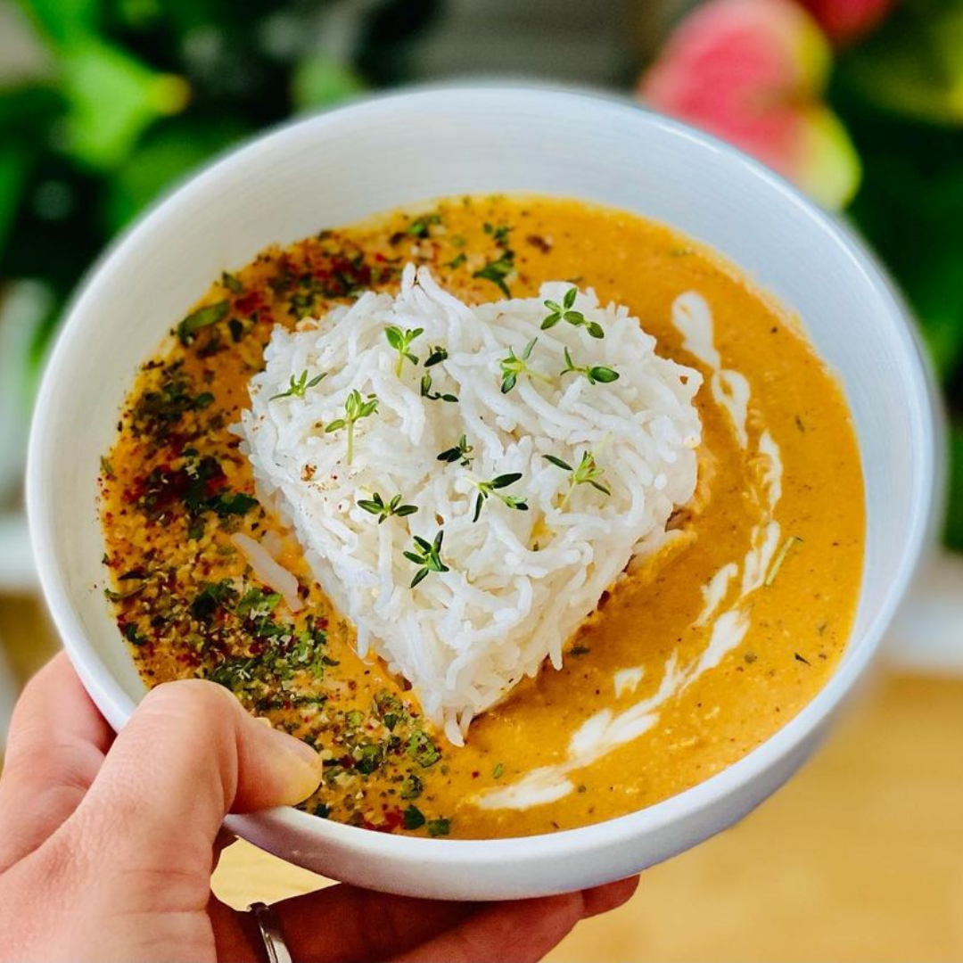 Herzförmiger Reis auf Curry in einer Schüssel, Hand haltend.