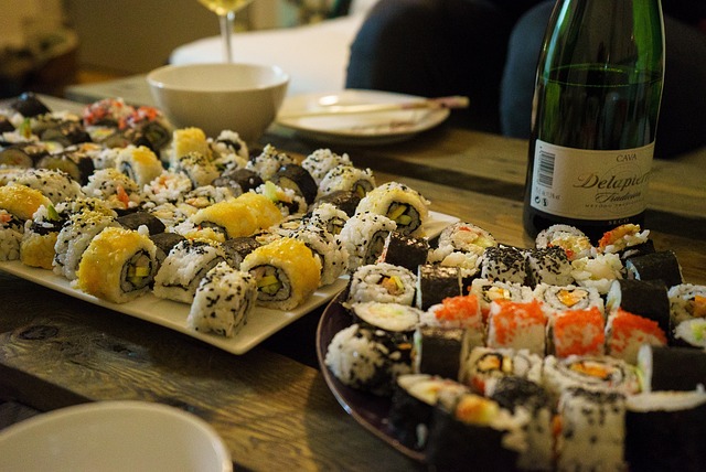 Variety of sushi rolls on plates with wine.