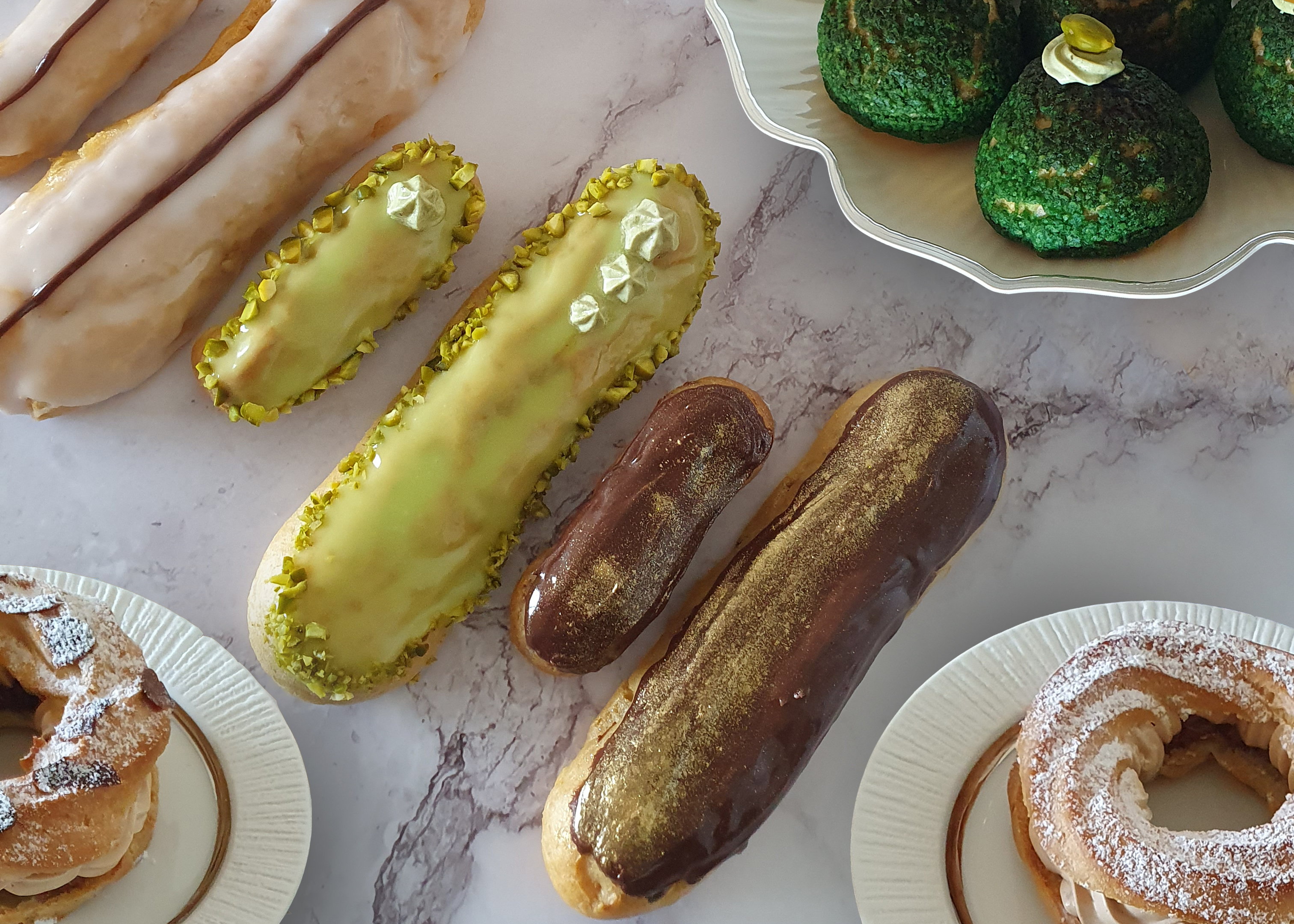 Assorted eclairs and pastries on marble surface.