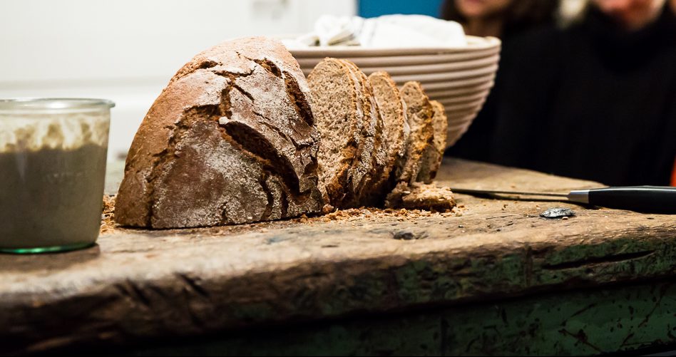 Bread is sliced on a rustic wooden board.