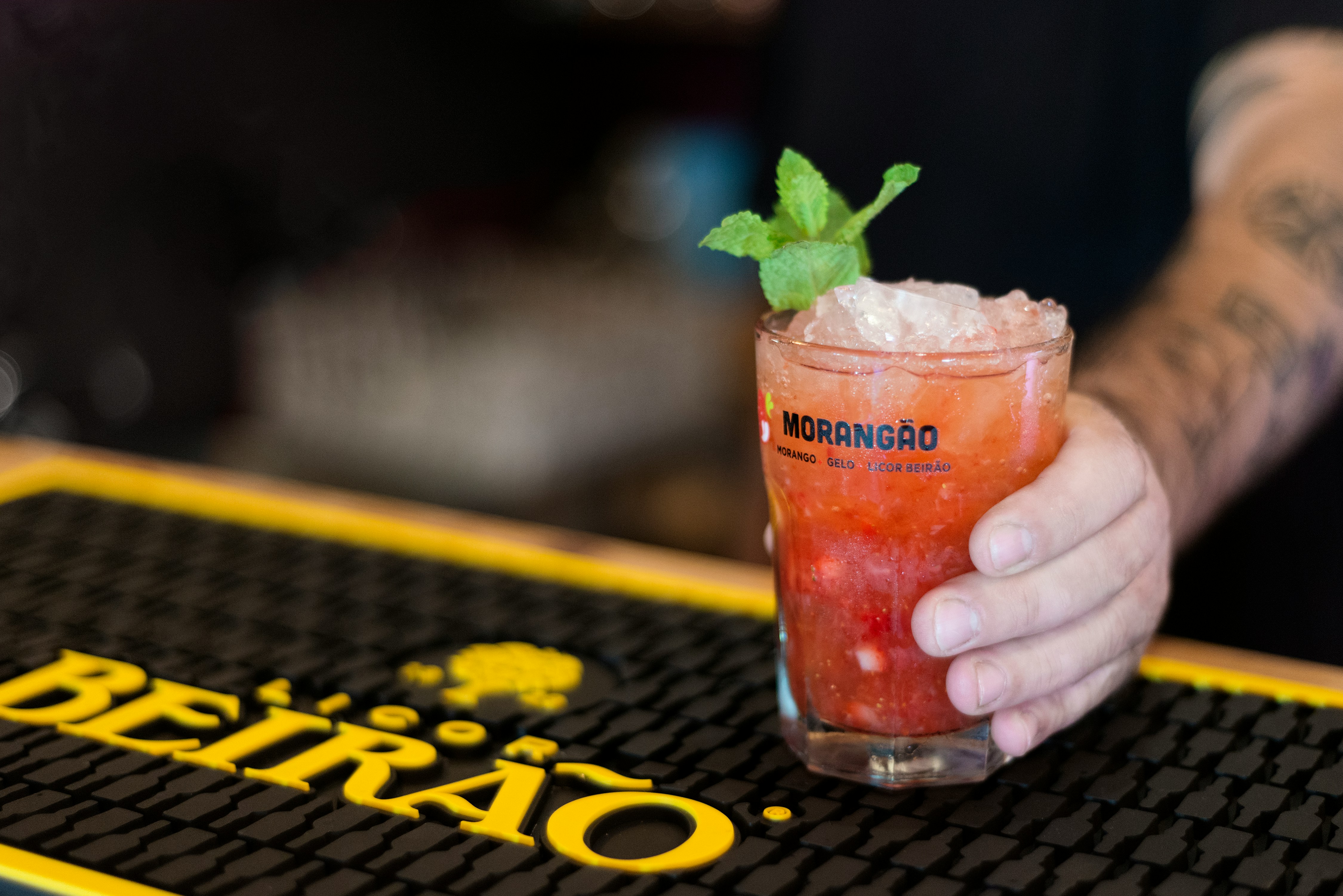 Hand haltend einen Erdbeercocktail mit Minzgarnitur.