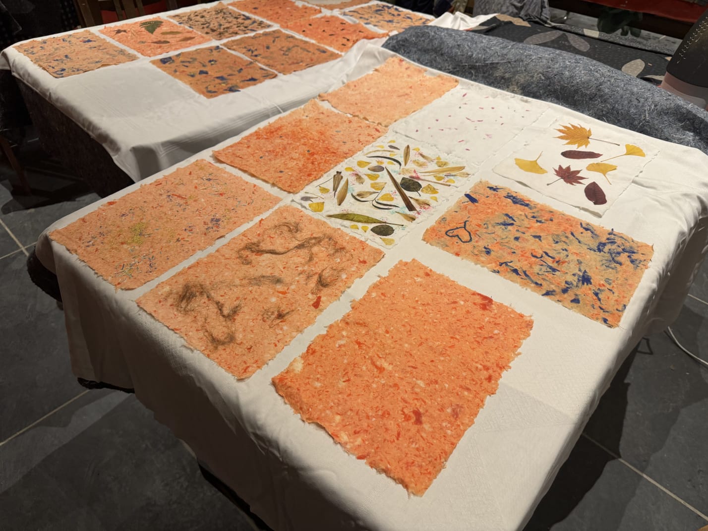 Handgemachte Papierblätter mit Blumenmustern auf Tischen.