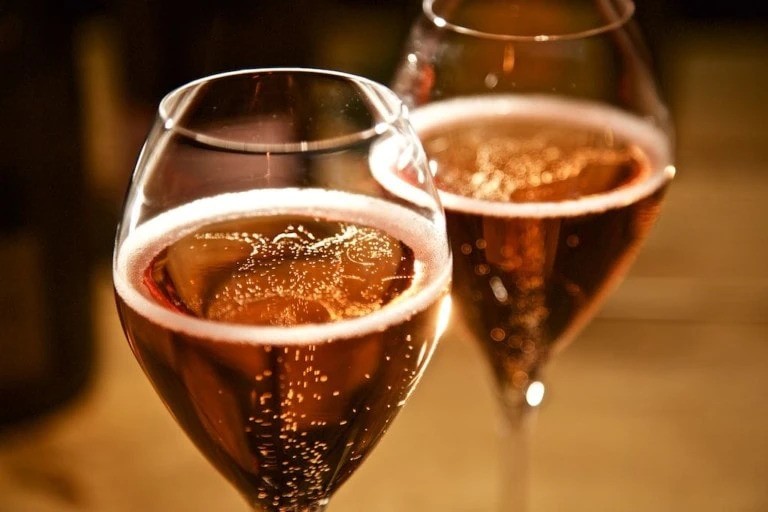 Two glasses of sparkling rosé wine on table.