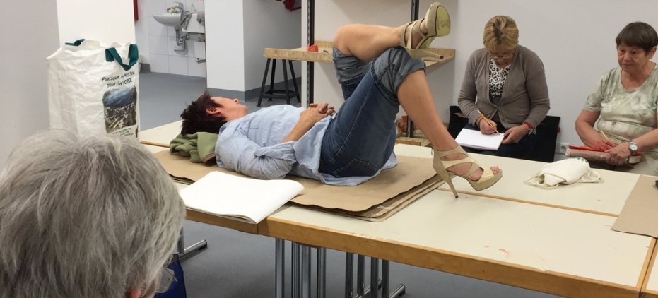 Modelnde Person auf dem Tisch, Künstler skizzieren in der Nähe.
