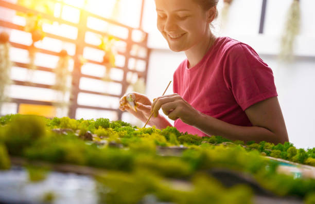 Person crafting with green moss art piece.