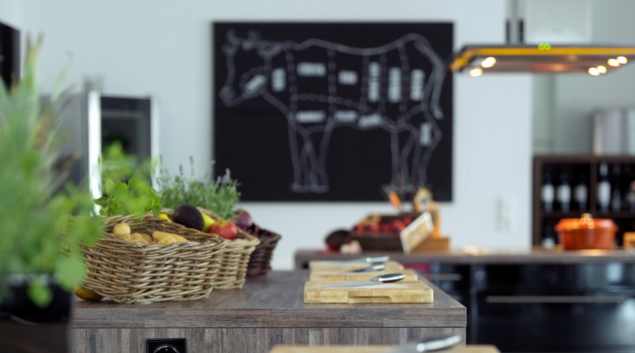 Basket of fresh vegetables stands on a wooden work surface.