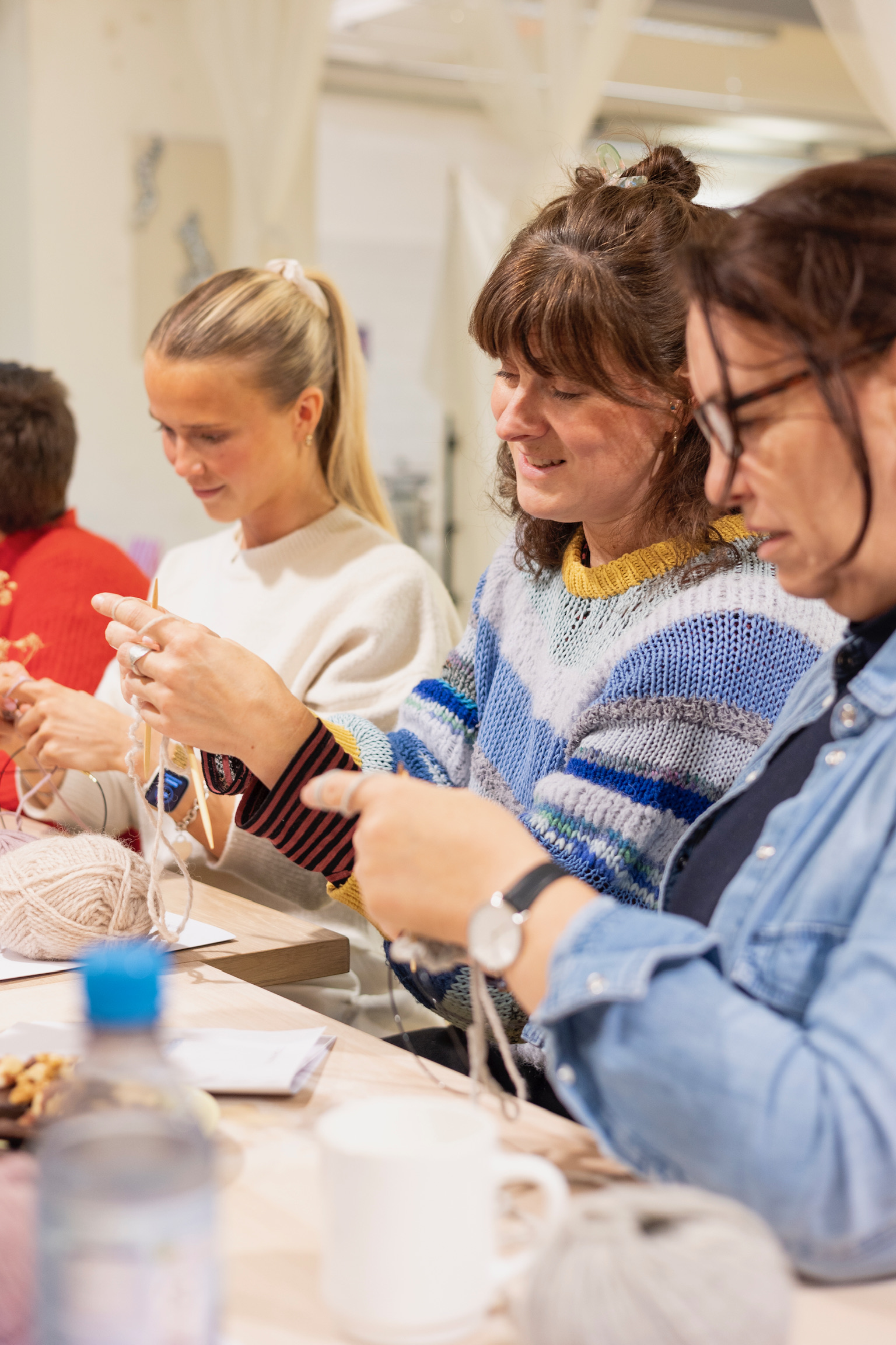 Gruppe von Frauen, die drinnen zusammen stricken.