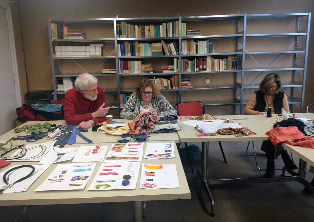 Three people working with fabric at tables in library.