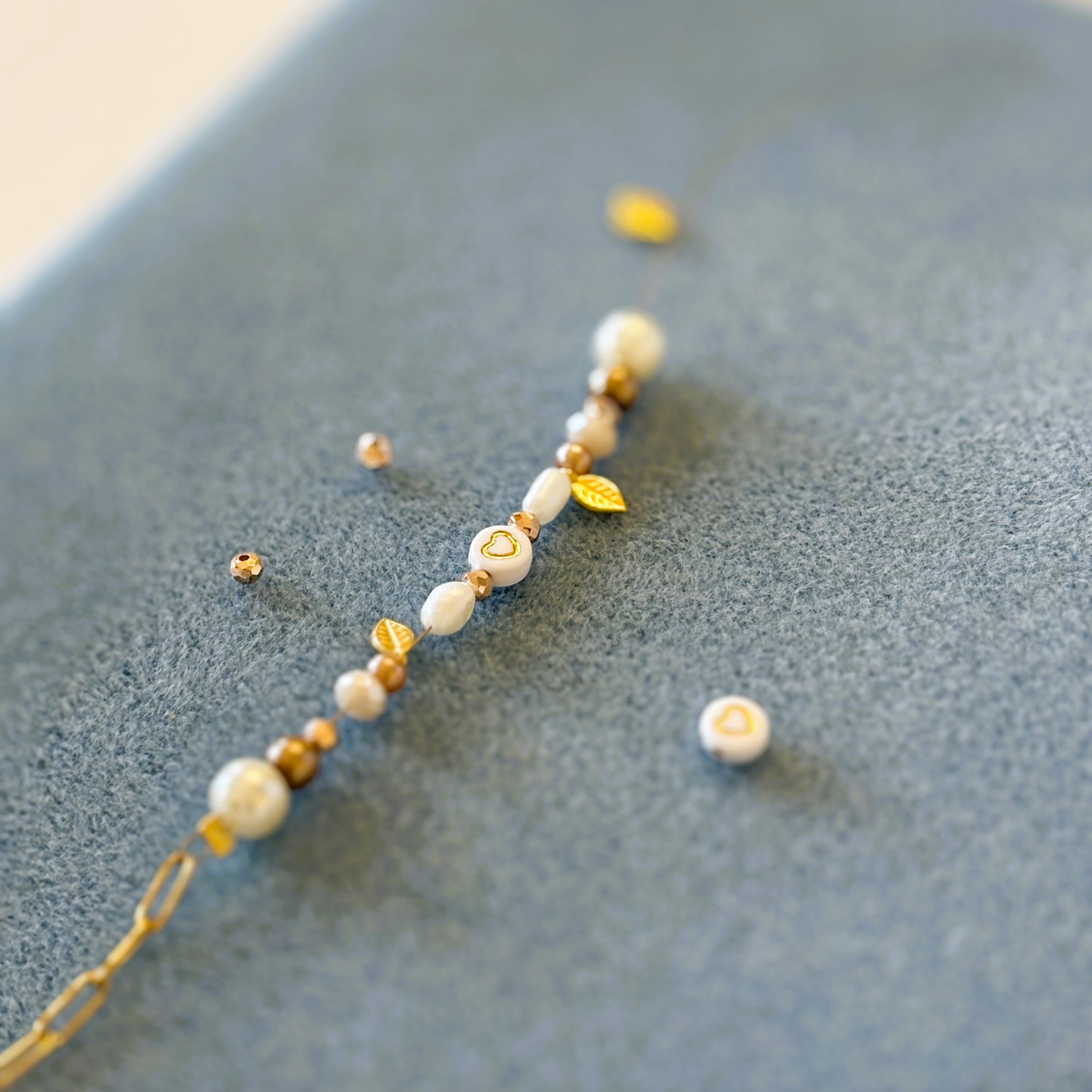 Beaded bracelet with heart and leaf charms.