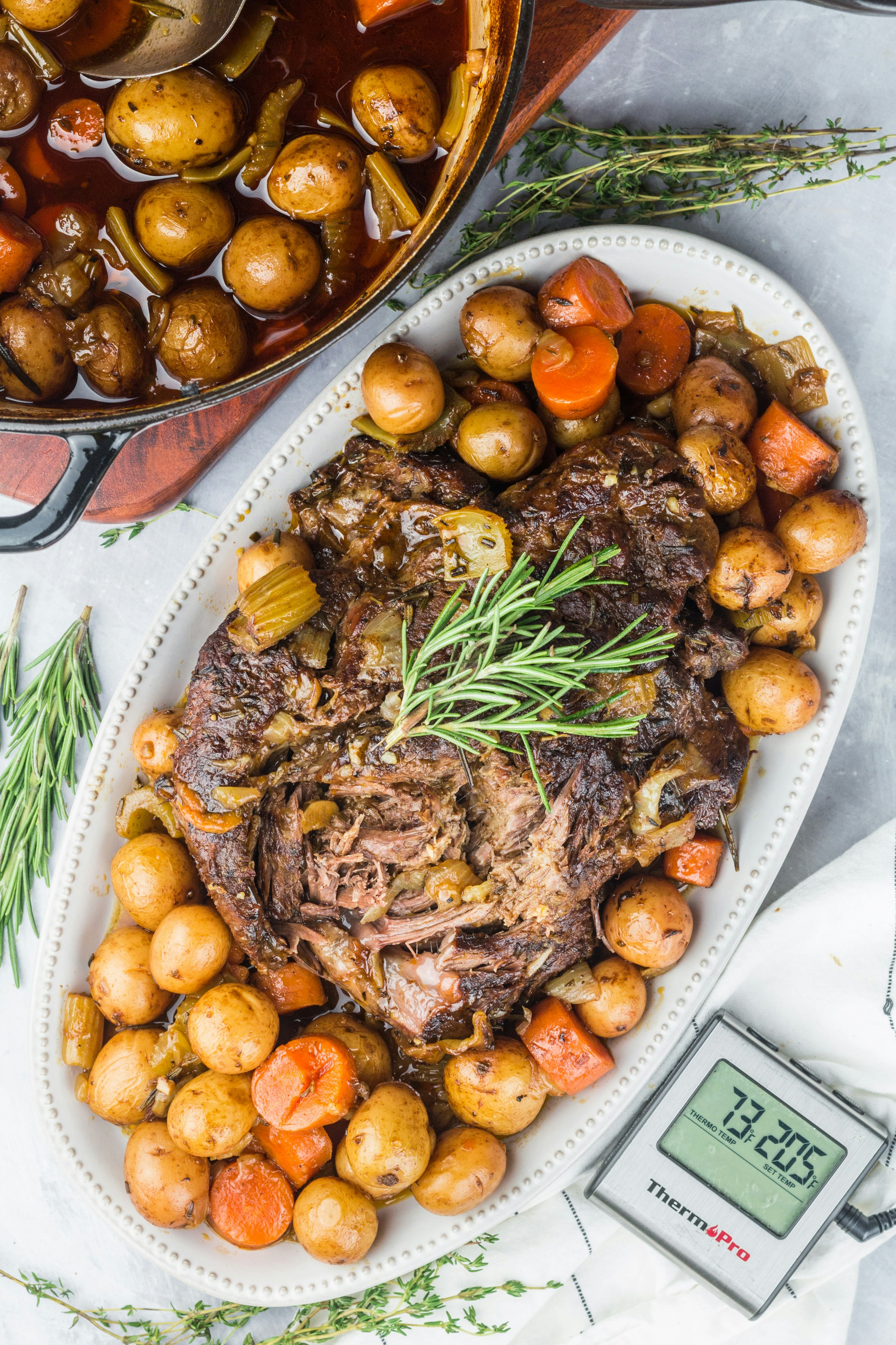 Cooked pot roast with potatoes and rosemary garnish.