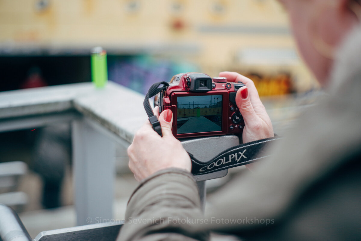 Person holding camera outdoors, capturing scene.