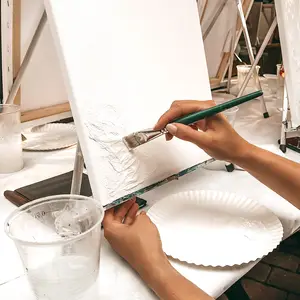 Hand painting on canvas at easel.