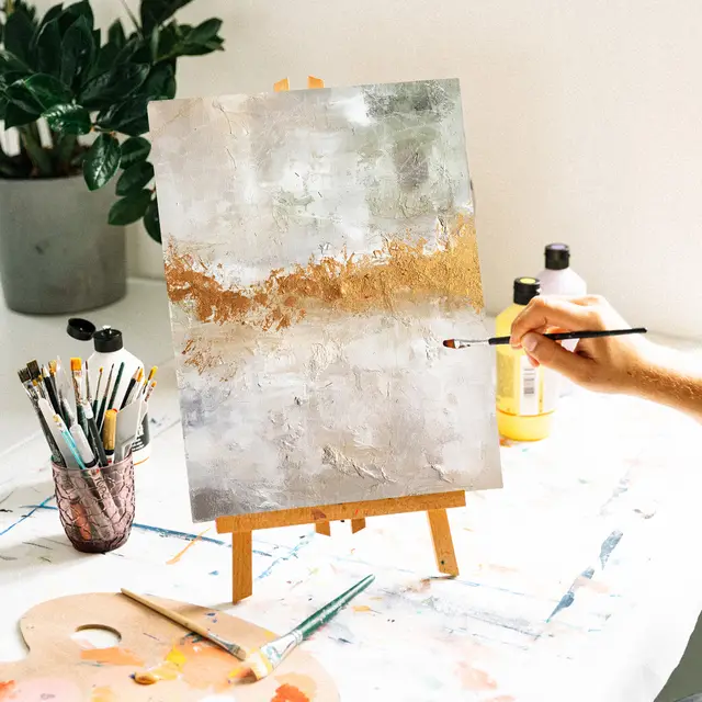 Person, die abstrakte Kunst auf einer kleinen Staffelei malt.