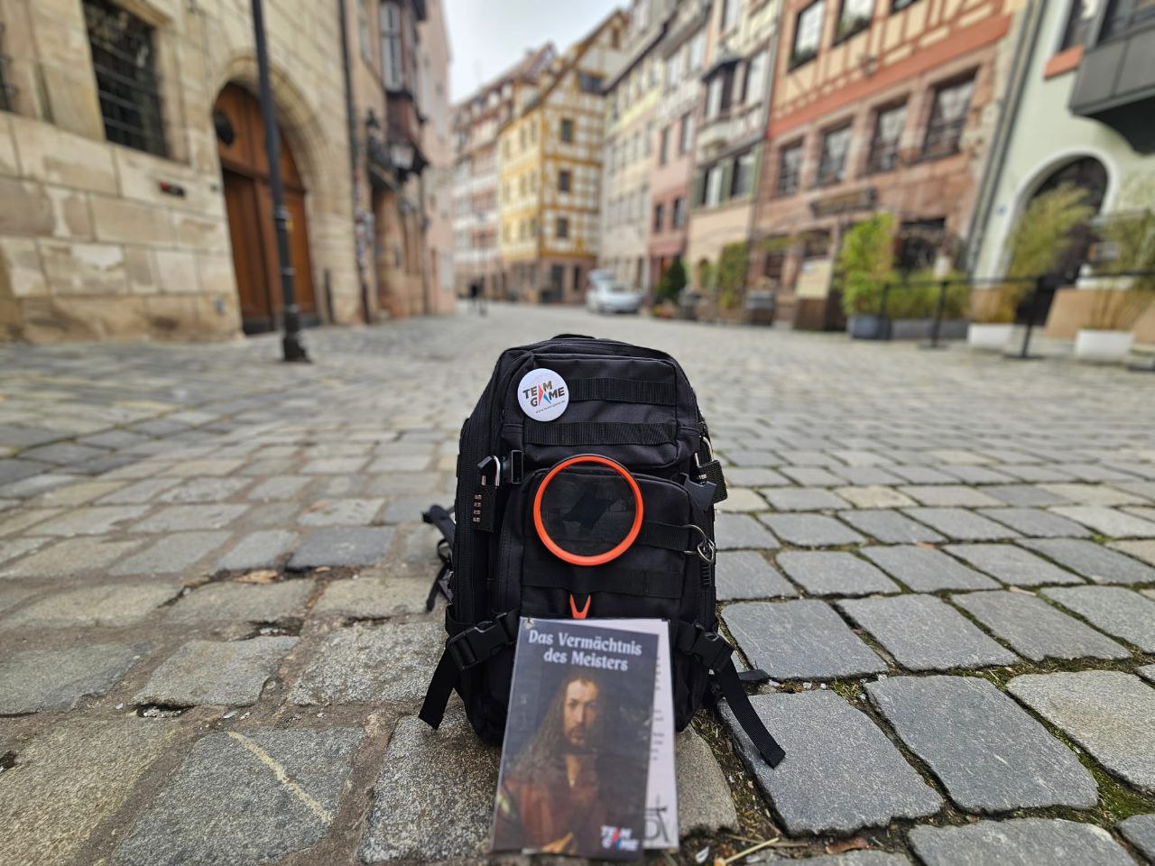 Rucksack und Buch auf der Kopfsteinpflasterstraße.